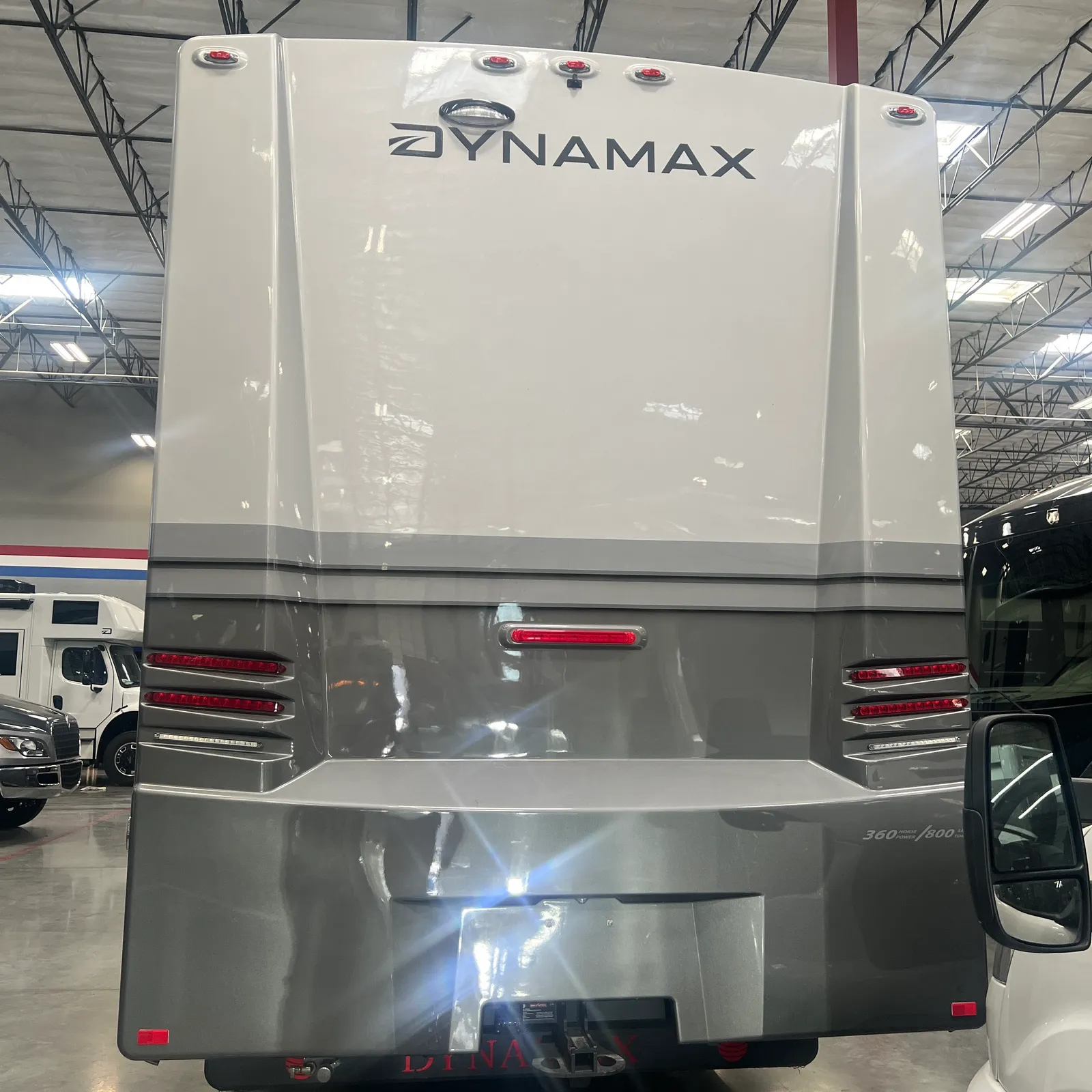 2027 Dynamax Corp Europa S 37CA Super C motorhome, rear view of white and gray motorhome with red taillights and chrome trim