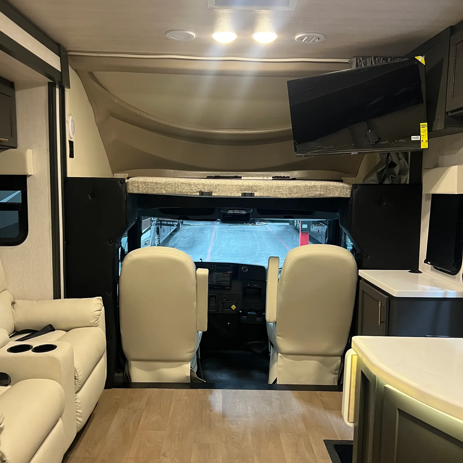 2027 Nexus Ghost 36DS Super C motorhome, living area with cream leather seating, tv, and view toward cockpit