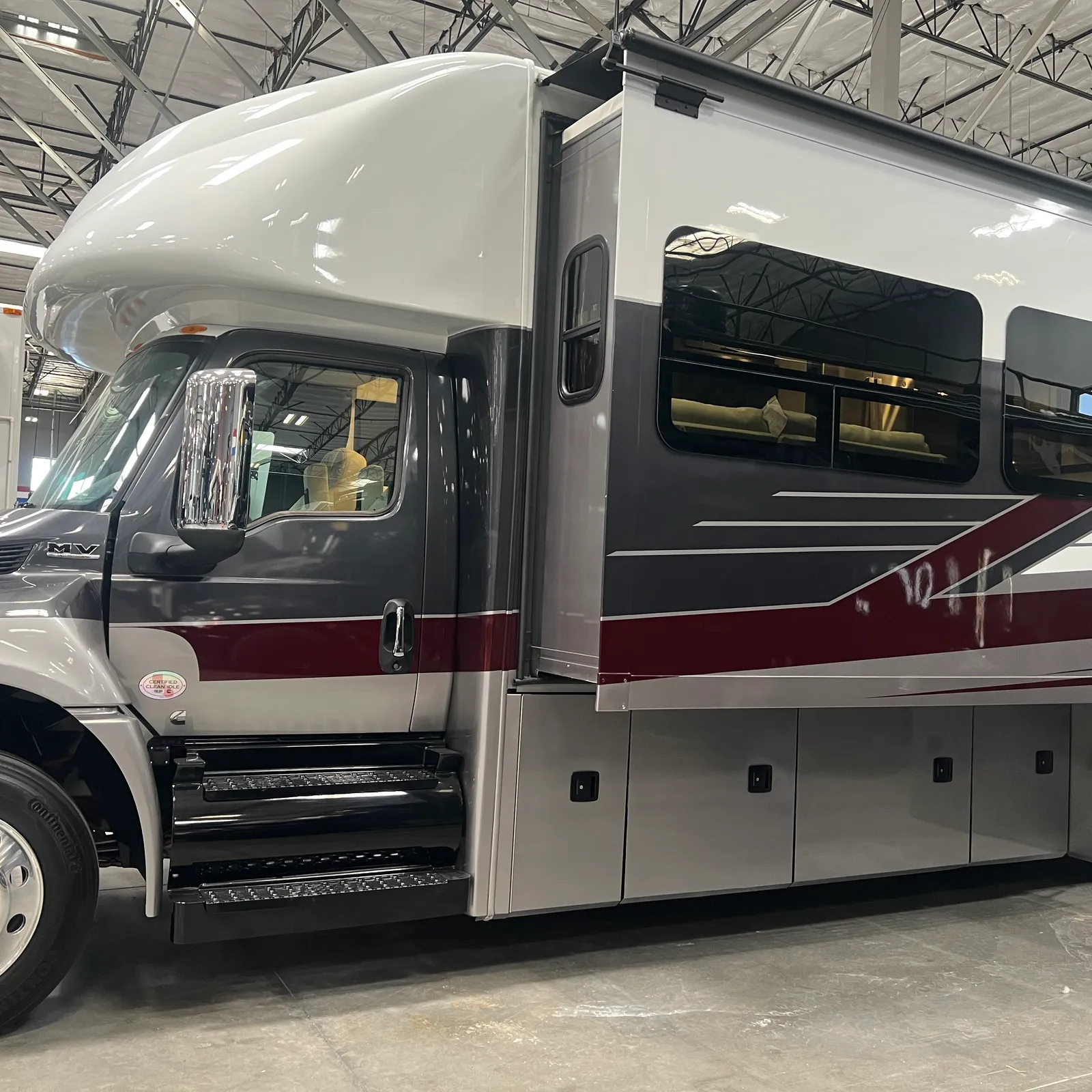 2027 Nexus Ghost 36DS Super C motorhome, side view of motorhome with white and burgundy exterior and open entry door