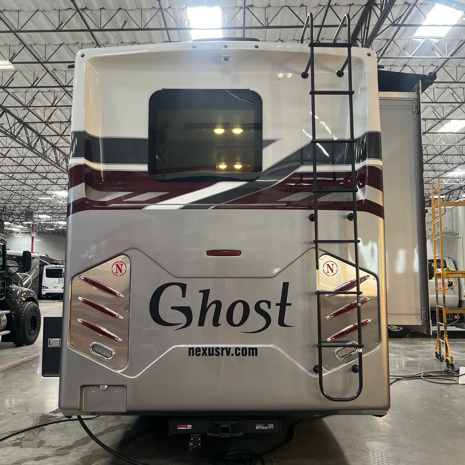 2027 Nexus Ghost 36DS Super C motorhome, rear view of motorhome with burgundy stripe and black ladder