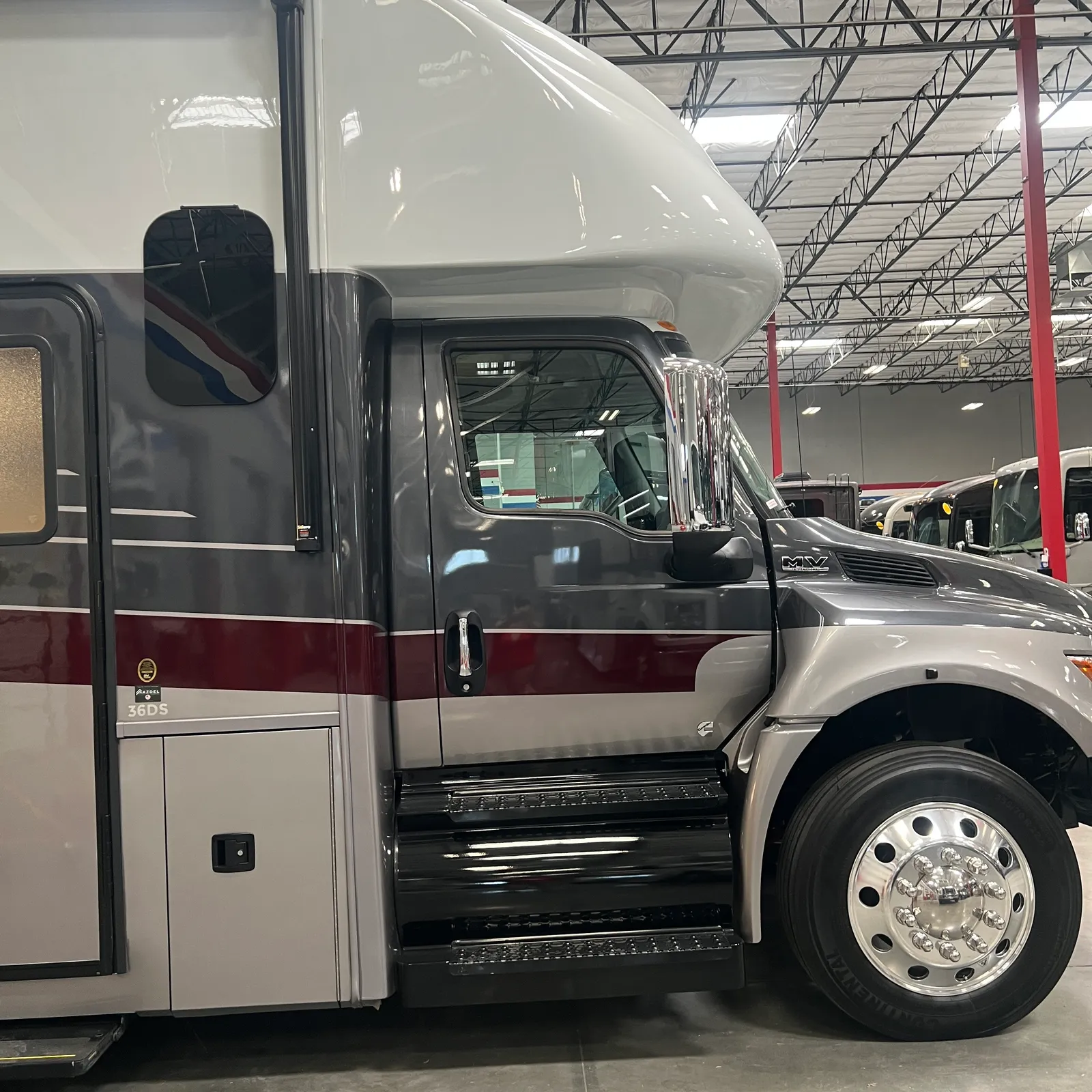 2027 Nexus Ghost 36DS Super C motorhome, motorhome cockpit and driver's side with open door in warehouse
