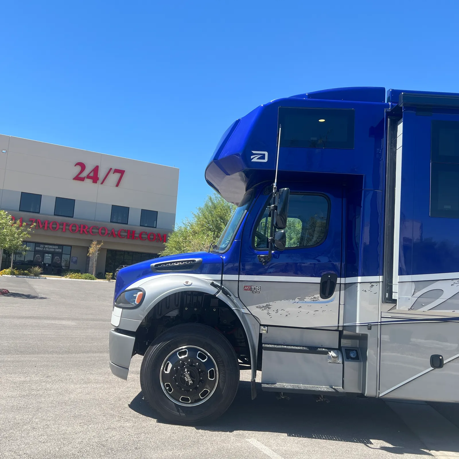 2027 Dynamax Corp DX3 32KD Super C motorhome, blue and silver motorhome with cab-over design and open entry door