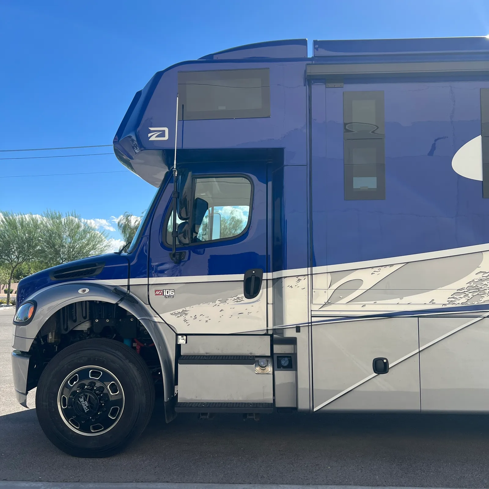 2027 Dynamax Corp DX3 32KD Super C motorhome, blue and white motorhome with open entry door under clear sky