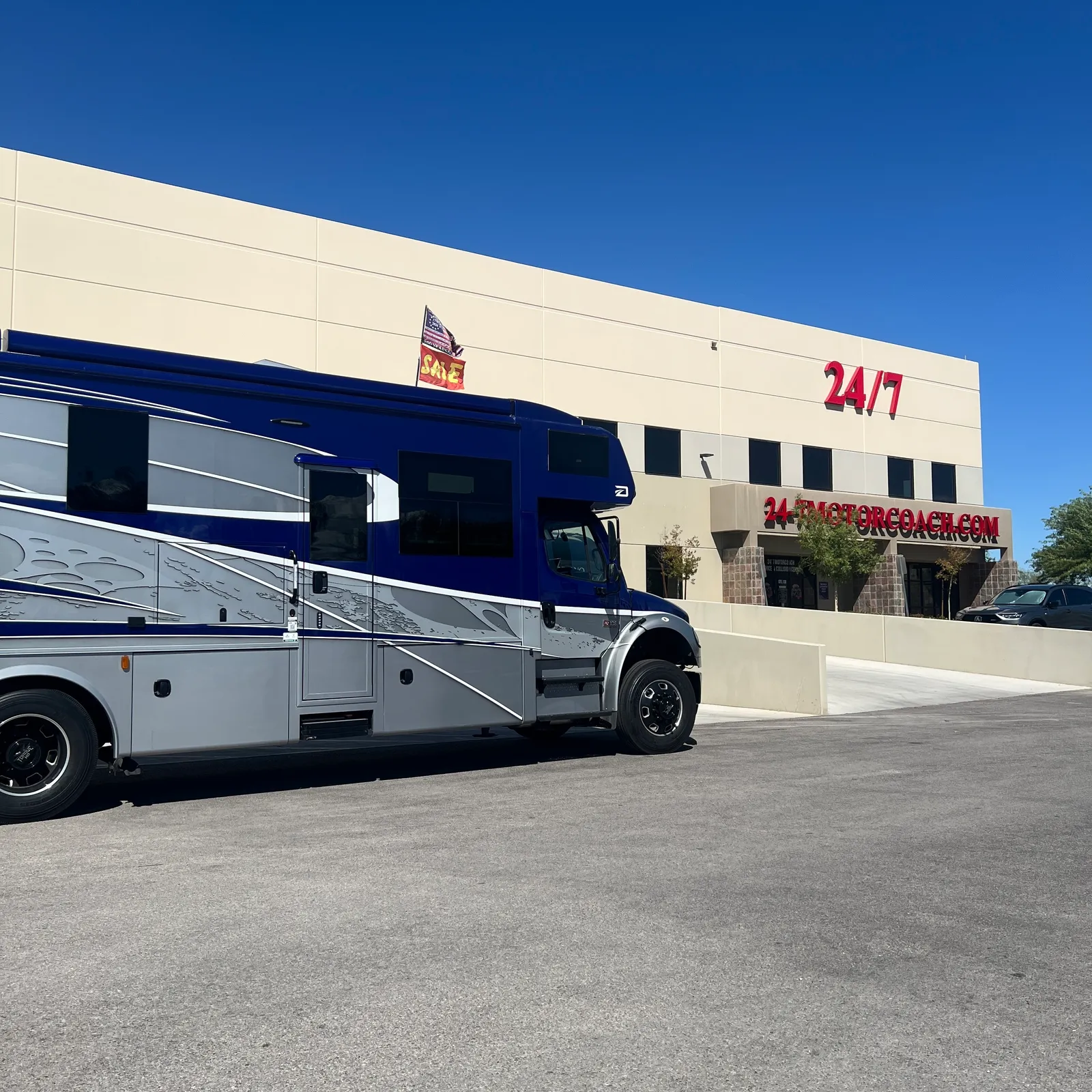 2027 Dynamax Corp DX3 32KD Super C motorhome, white and blue motorhome with blue stripe parked at dealership