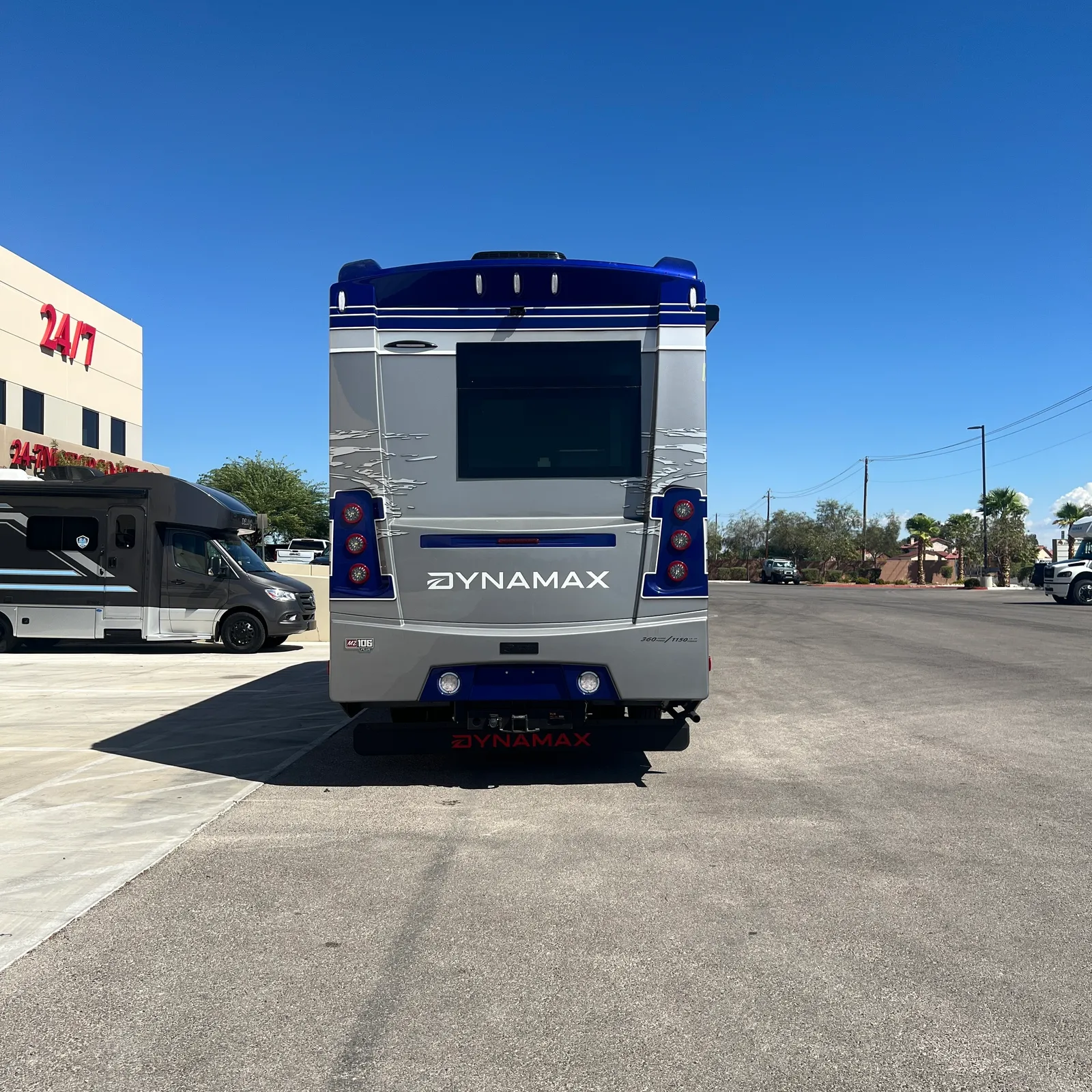 2027 Dynamax Corp DX3 32KD Super C motorhome, rear view of blue and gray motorhome in dealership lot