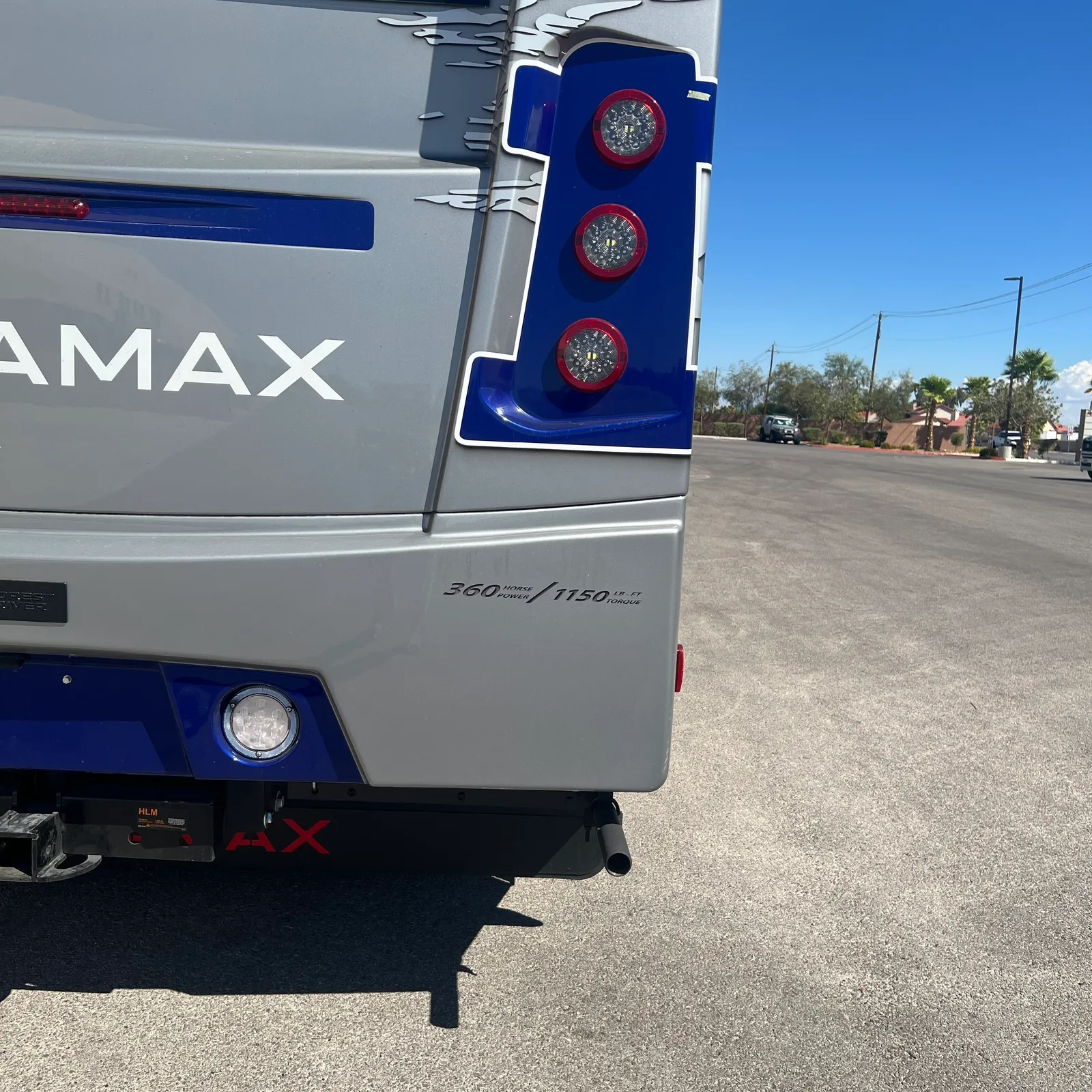 2027 Dynamax Corp DX3 32KD Super C motorhome, rear corner of motorhome with blue and white exterior and red taillights