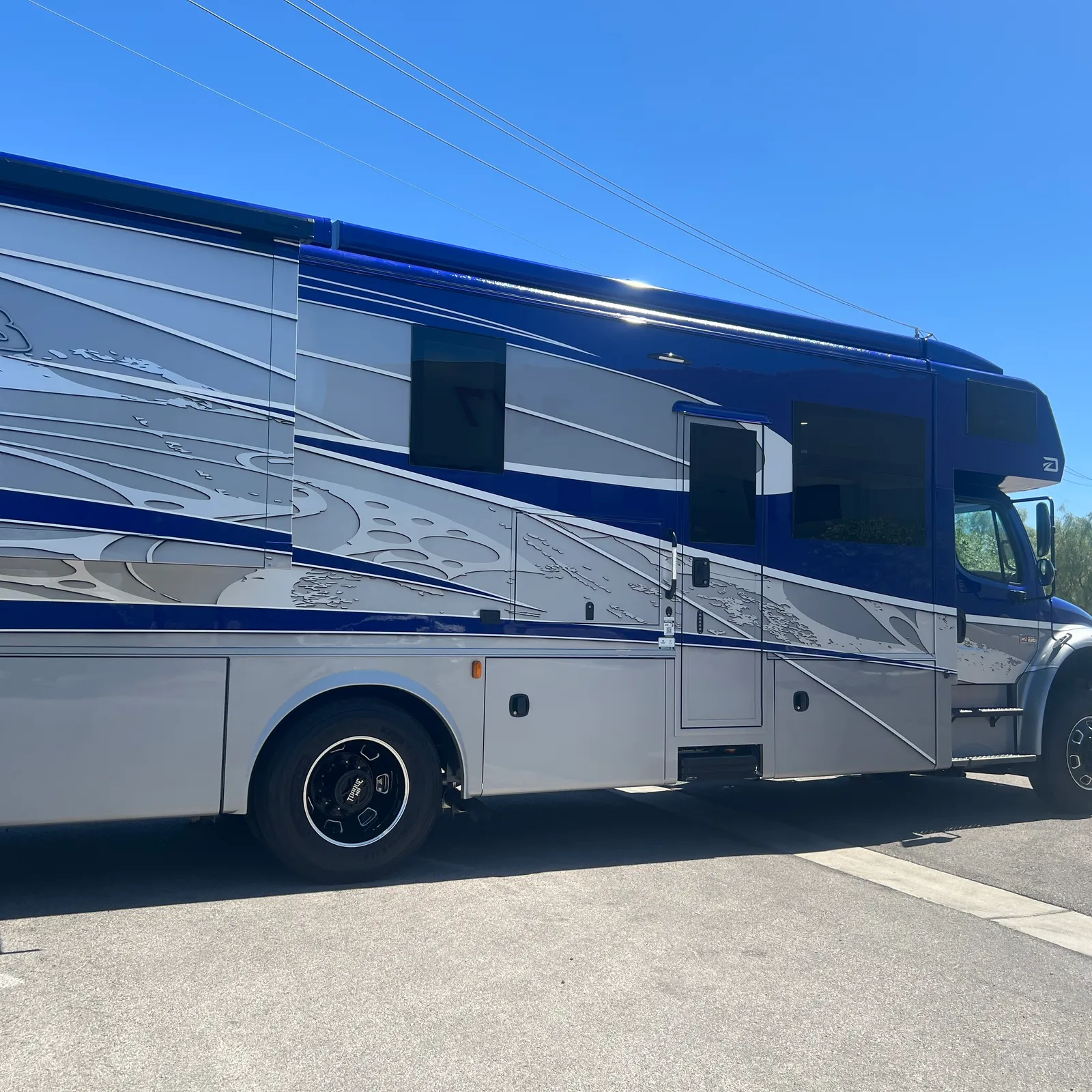 2027 Dynamax Corp DX3 32KD Super C motorhome, blue and silver motorhome with decorative graphics and side windows