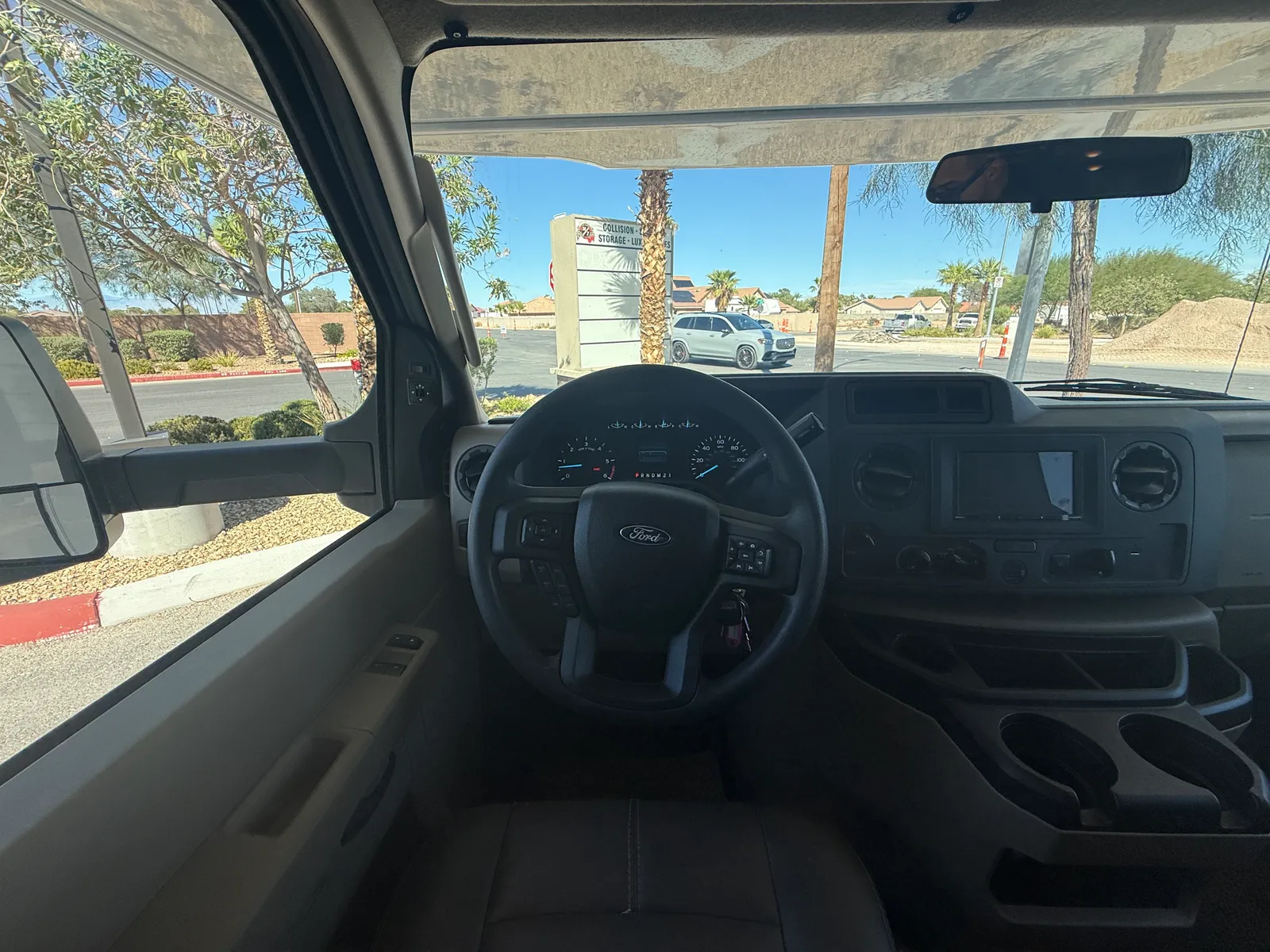 2023 Thor Motor Coach Geneva Class C motorhome, driver's area with steering wheel and dashboard, view through windshield to parking lot