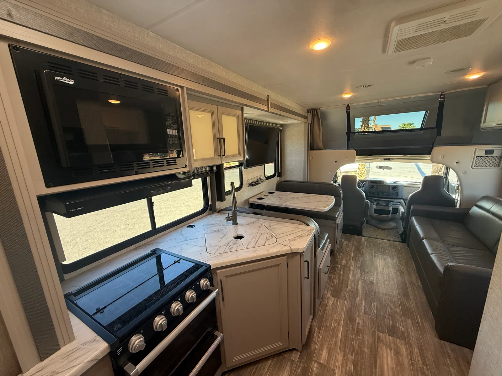 2023 Thor Motor Coach Geneva Class C motorhome, open living area with dinette seating, kitchen with stove and microwave, television, and cockpit