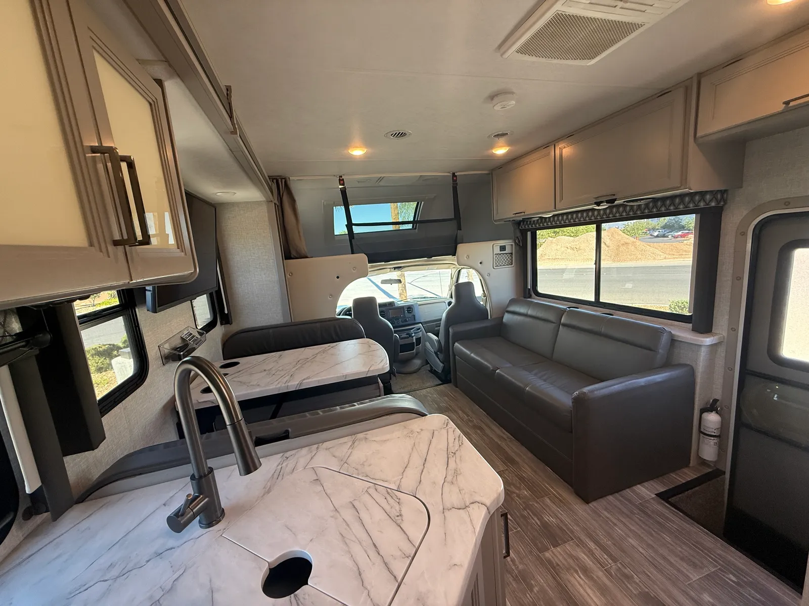 2023 Thor Motor Coach Geneva Class C motorhome, living area with dinette, sofa, and cockpit view forward