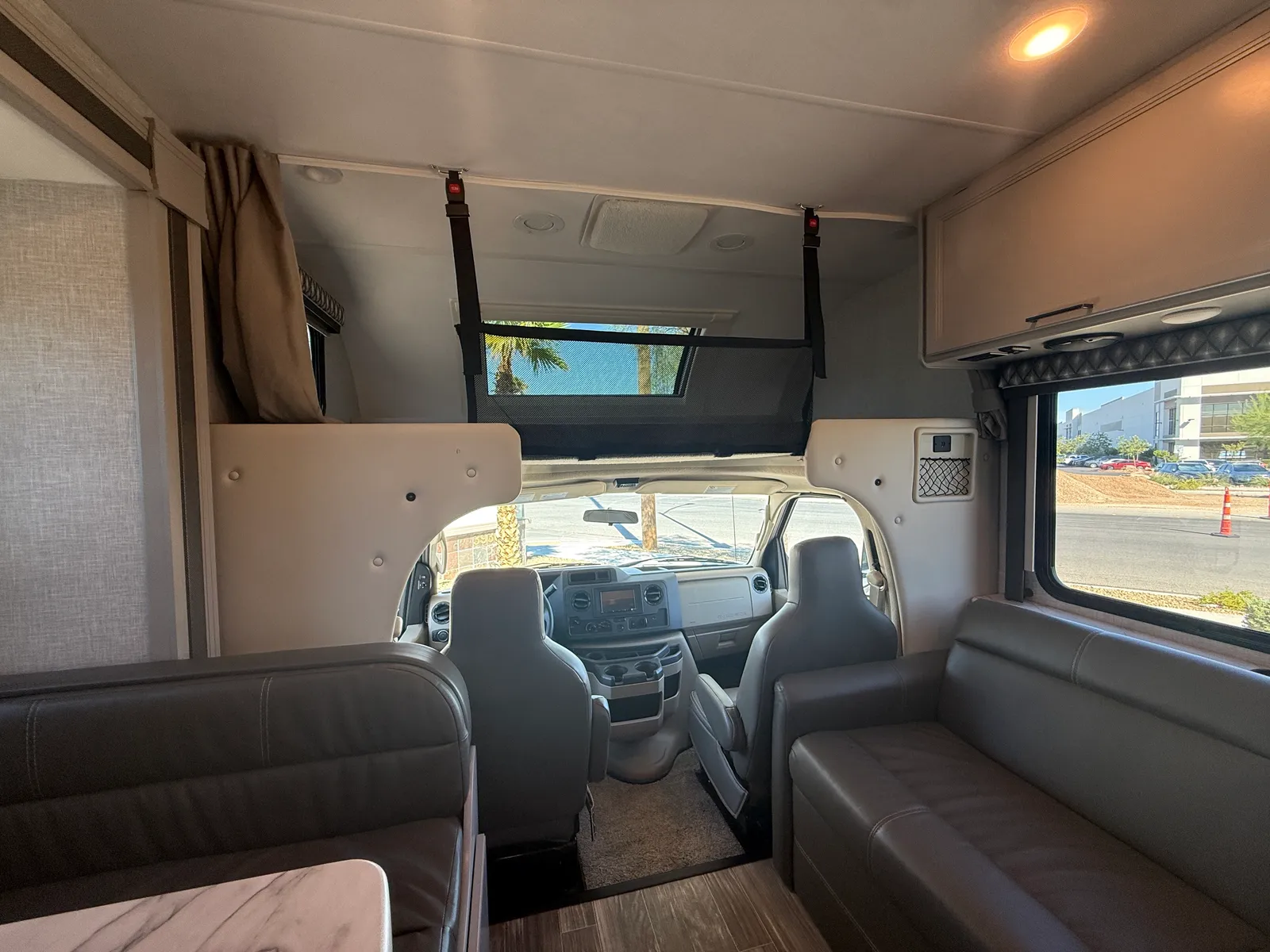 2023 Thor Motor Coach Geneva Class C motorhome, living area with seating, side windows, and view to cockpit