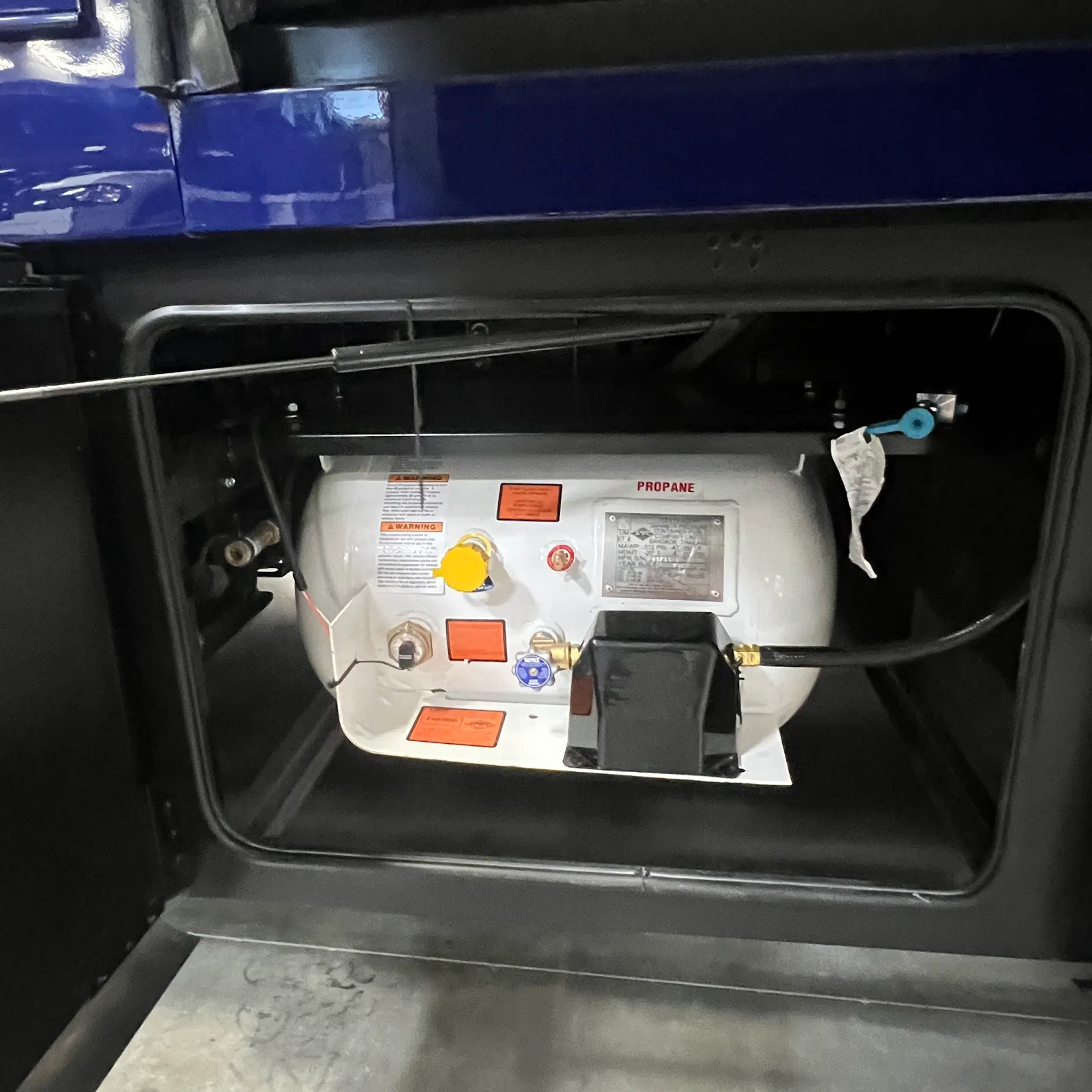 2027 Dynamax Corp Europa S 37CA Super C motorhome, propane tank and system with warning labels and connections in storage compartment