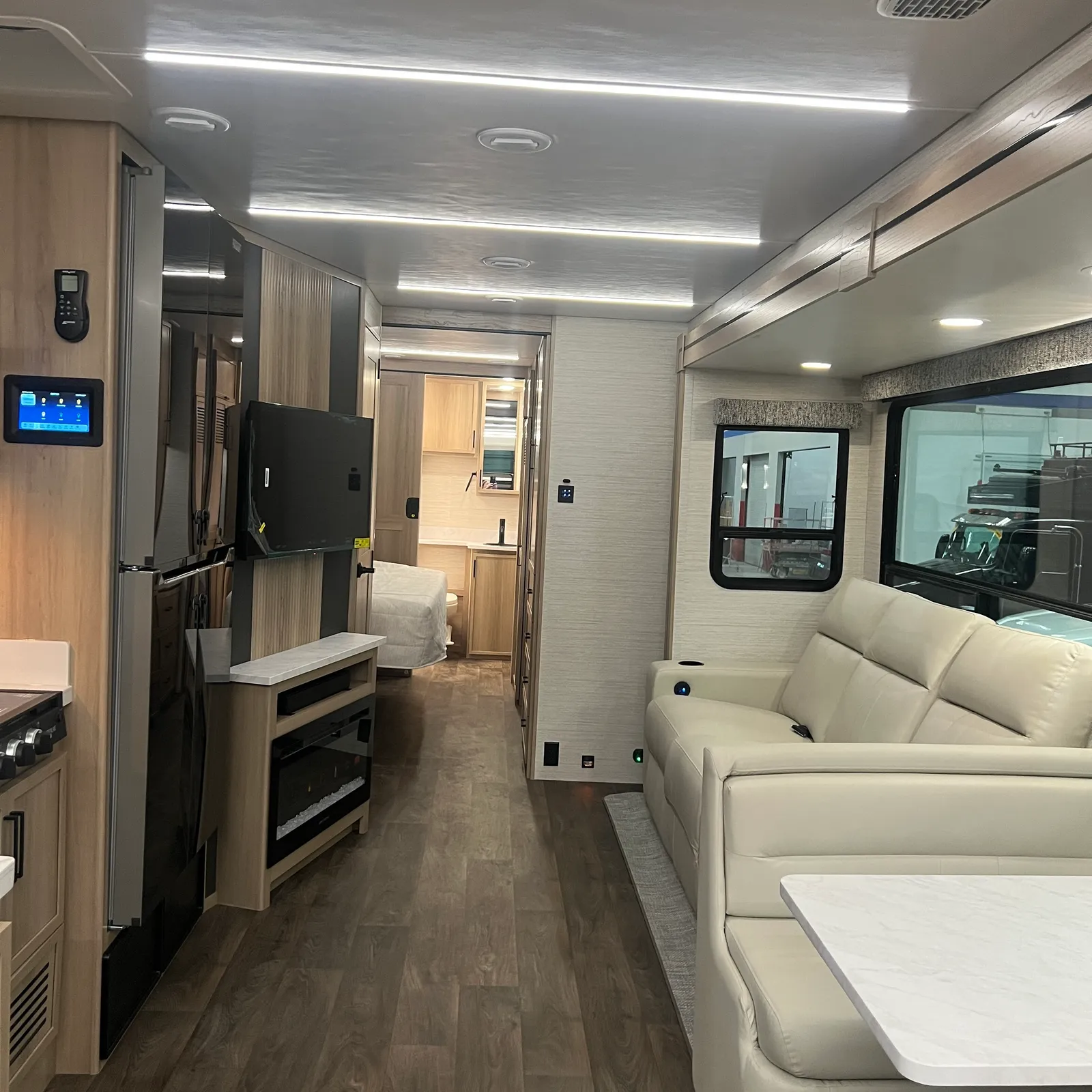 2027 Dynamax Corp Europa S 37CA Super C motorhome, living area with cream sofa, entertainment center, and galley kitchen