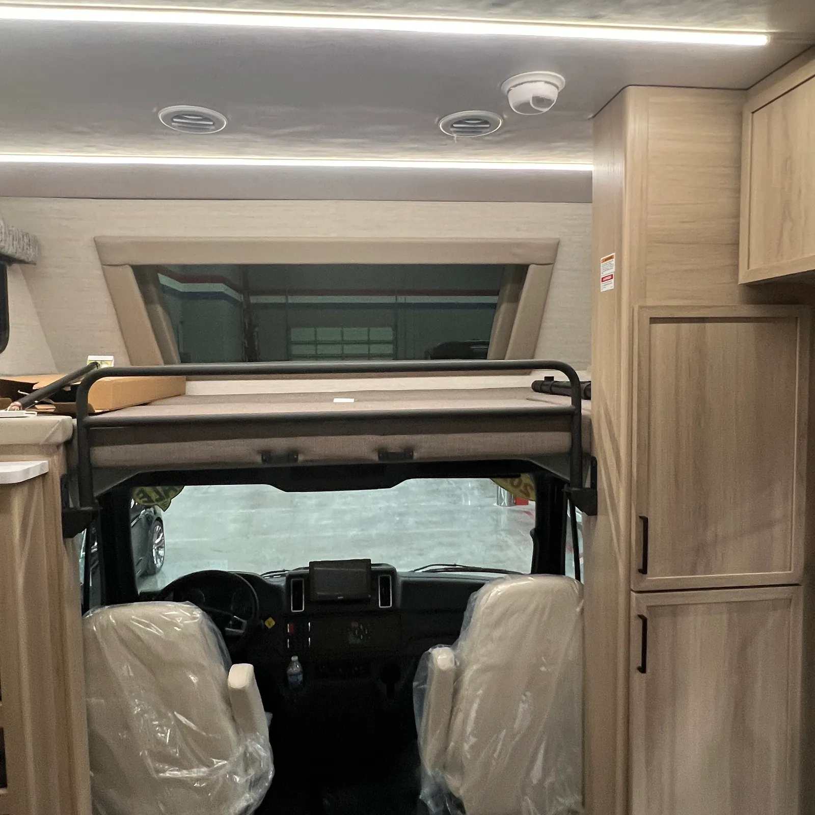 2027 Dynamax Corp Europa S 37CA Super C motorhome, cockpit with overhead bunk and driver seats covered in plastic