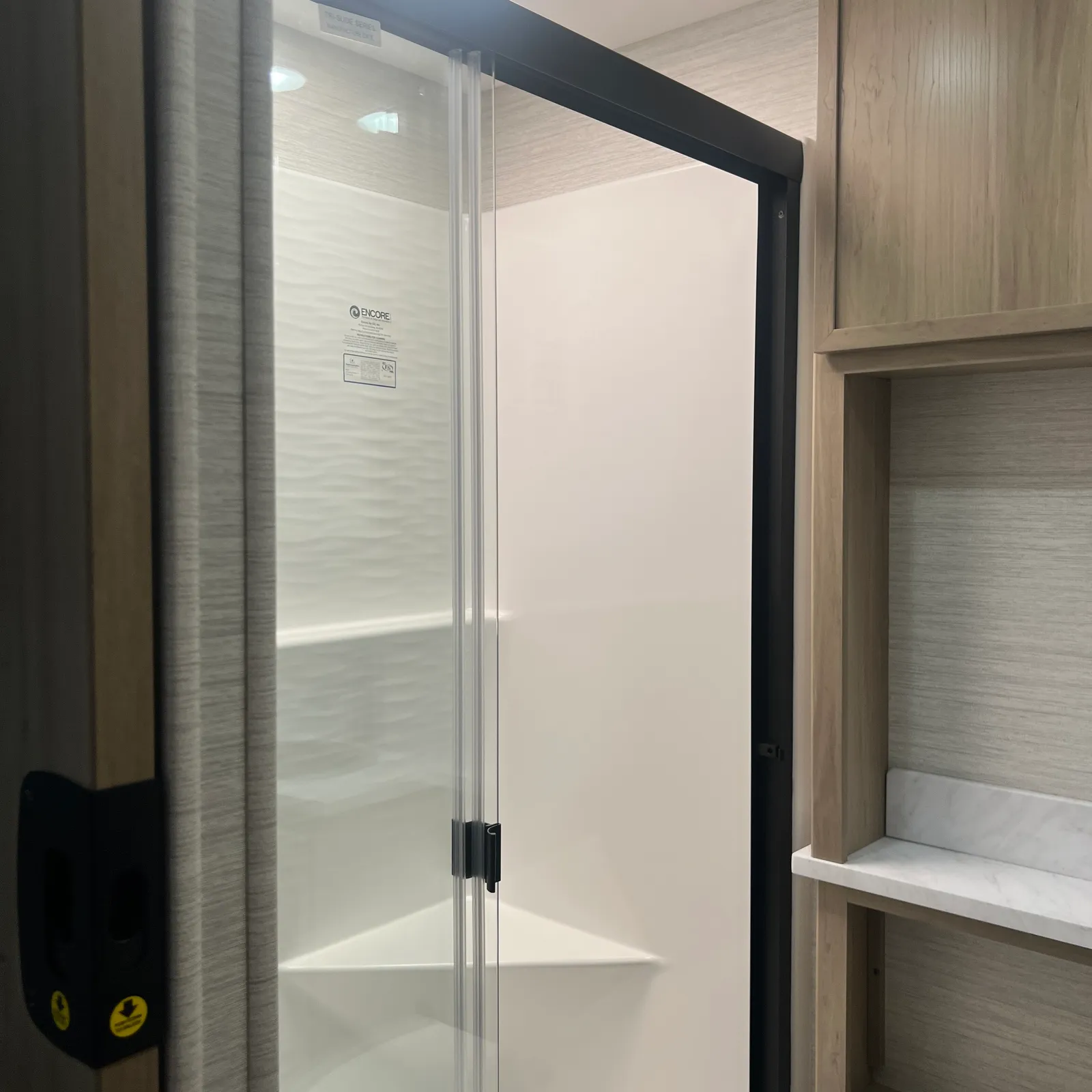 2027 Dynamax Corp Europa S 37CA Super C motorhome, glass shower enclosure with black frame and wood cabinetry