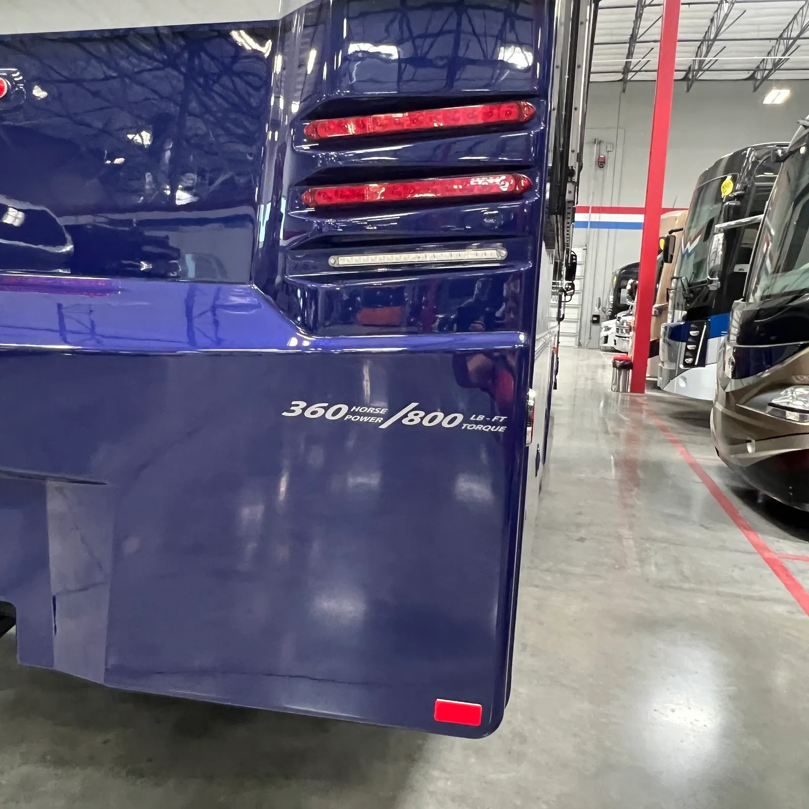 2027 Dynamax Corp Europa S 37CA Super C motorhome, rear exterior of blue motorhome with red taillights and power specifications