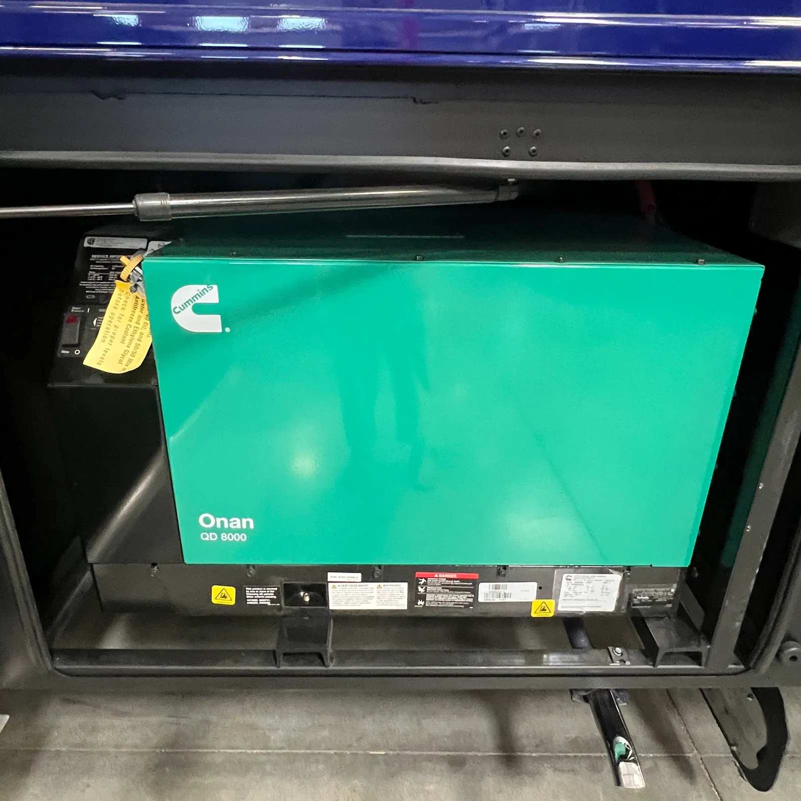 2027 Dynamax Corp Europa S 37CA Super C motorhome, generator compartment with onan qd 6000 unit and cummins badge