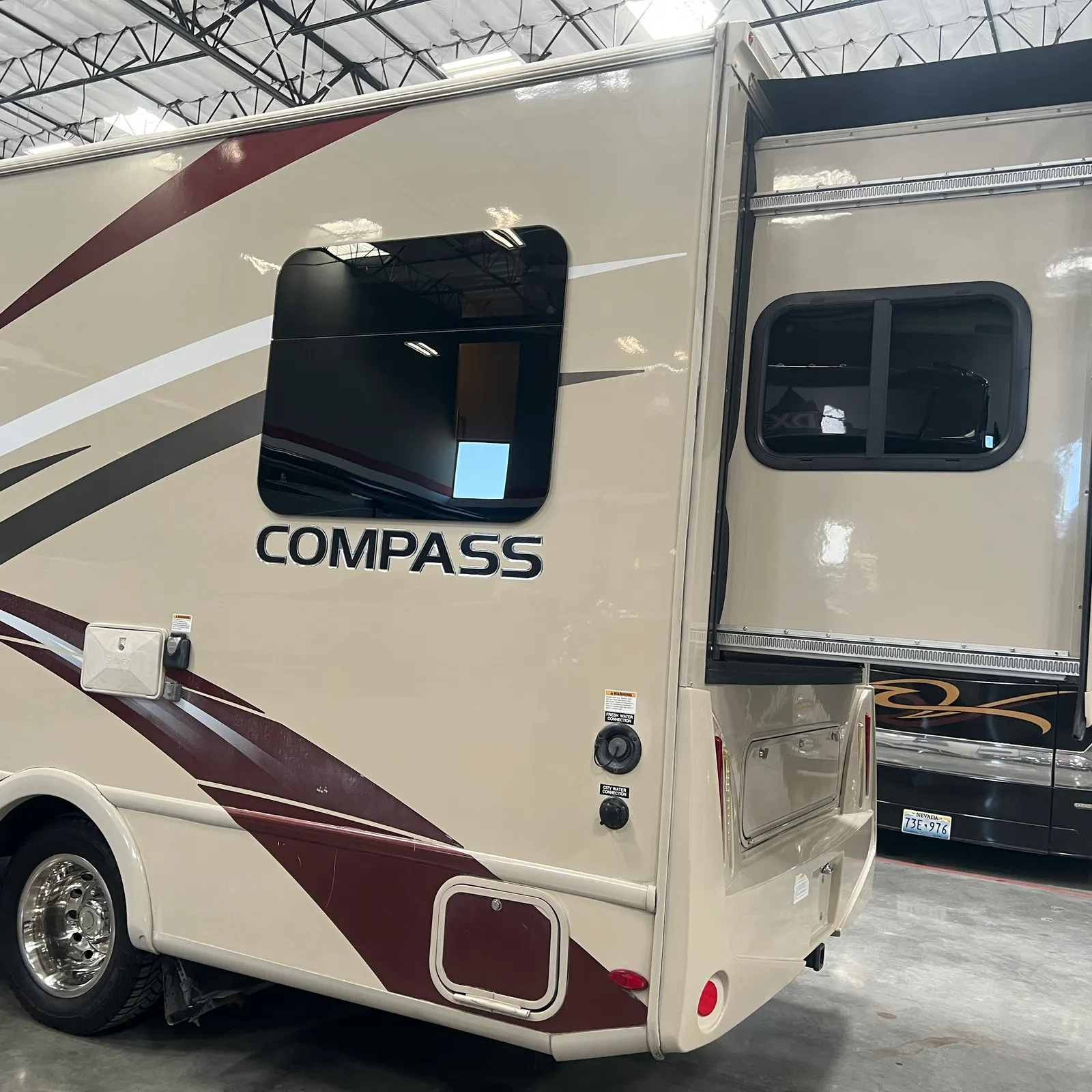 2018 Thor Motor Coach Compass 23TR Class C motorhome, motorhome side with compass logo, window, and door in indoor showroom