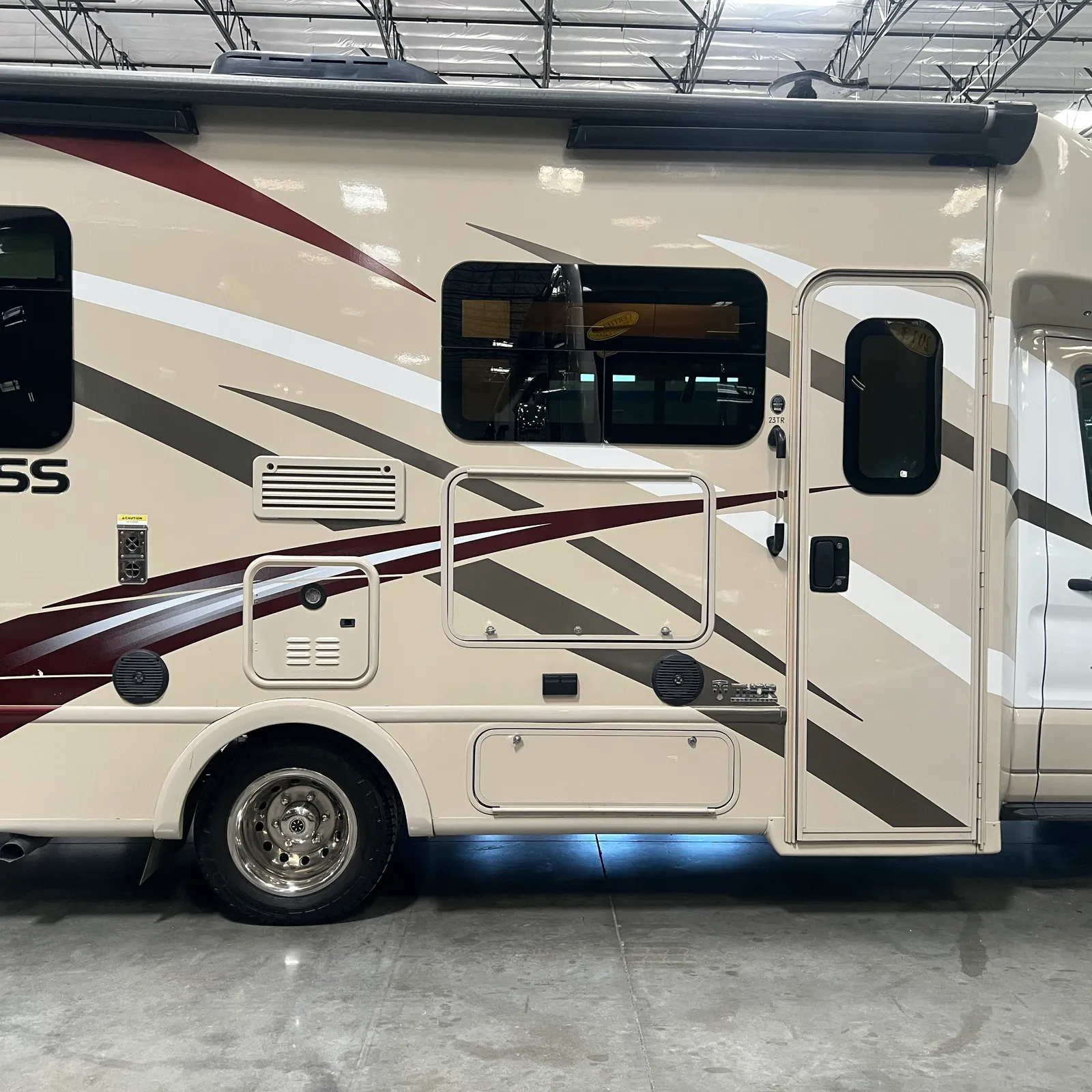 2018 Thor Motor Coach Compass 23TR Class C motorhome, side view of motorhome with windows, door, and decorative stripe detail