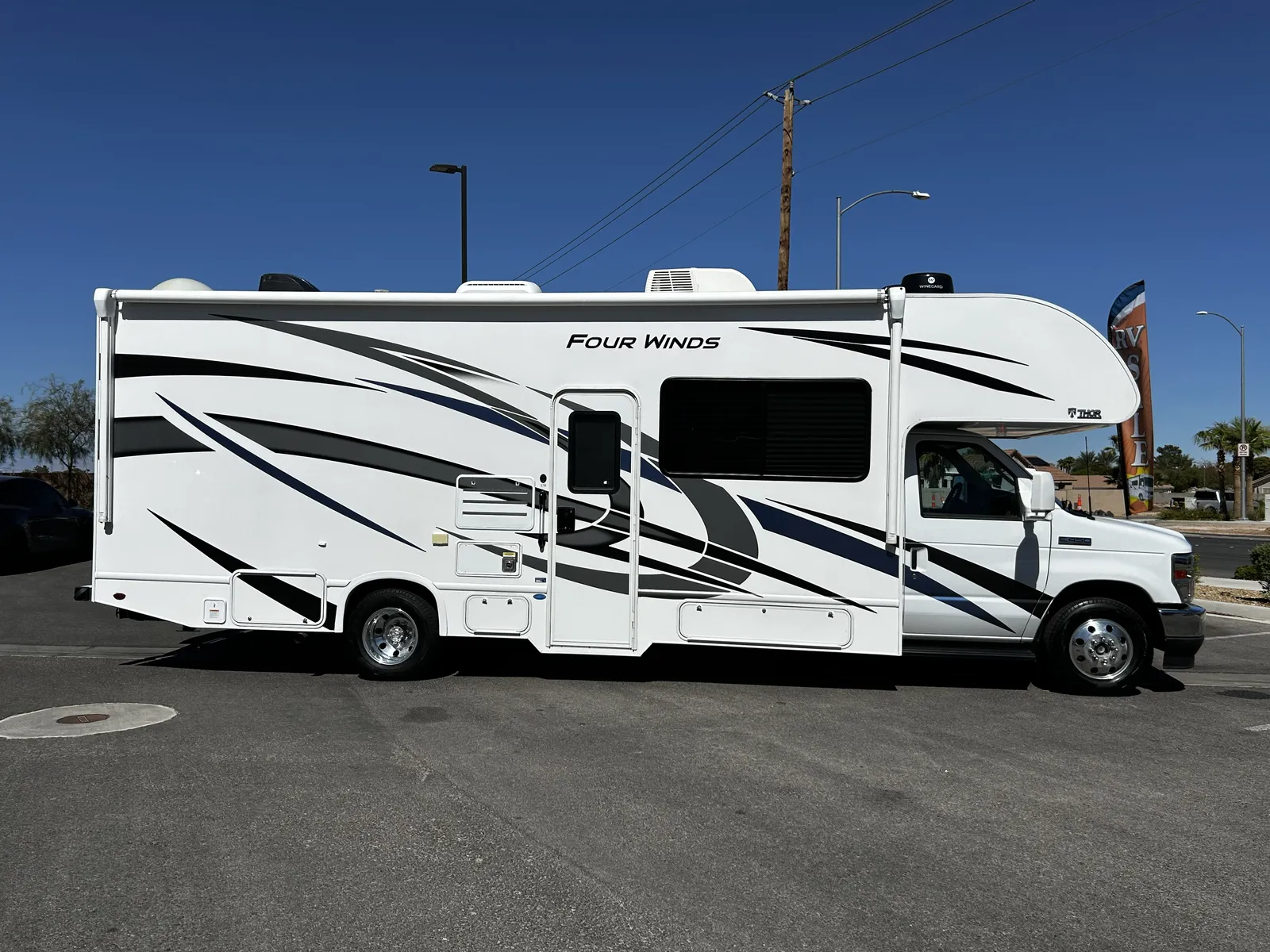 2023 Thor Motor Coach Four Winds Super C motorhome, white motorhome with black accent stripes and graphics parked in lot