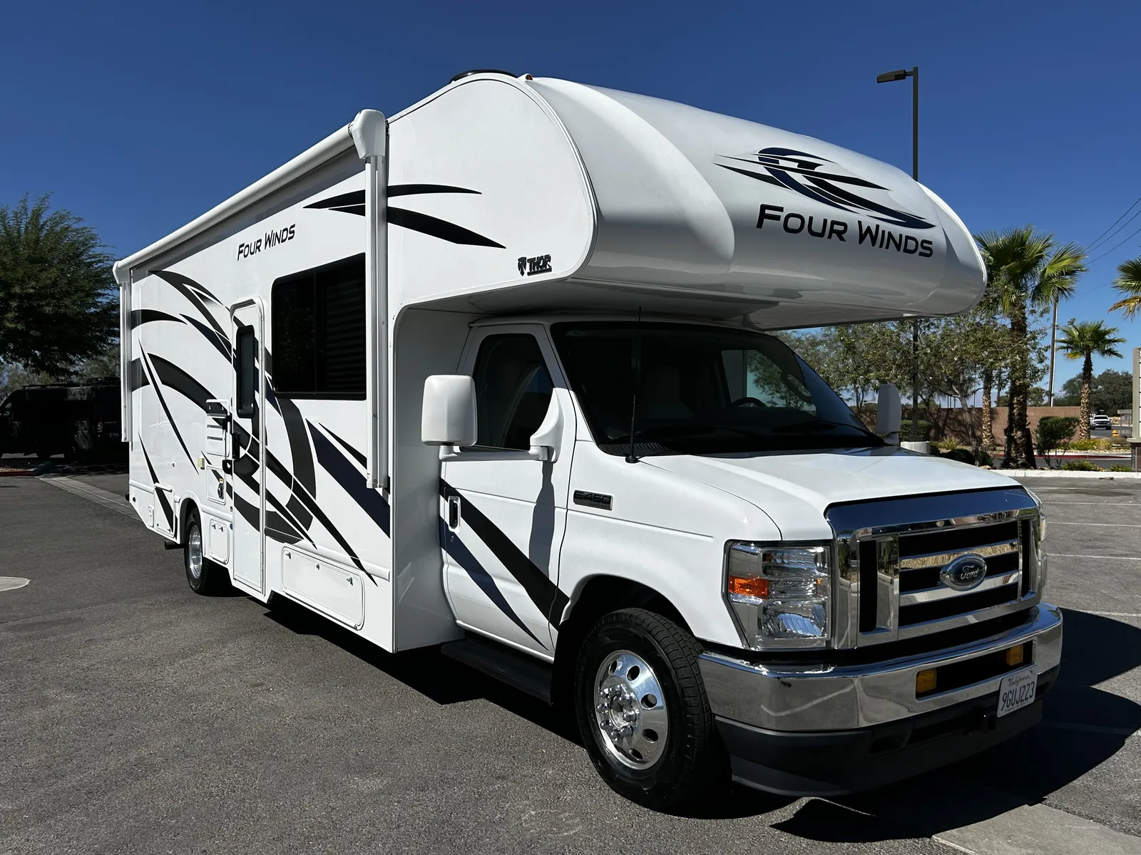 2023 Thor Motor Coach Four Winds Super C motorhome, white motorhome with black graphics and awning extended