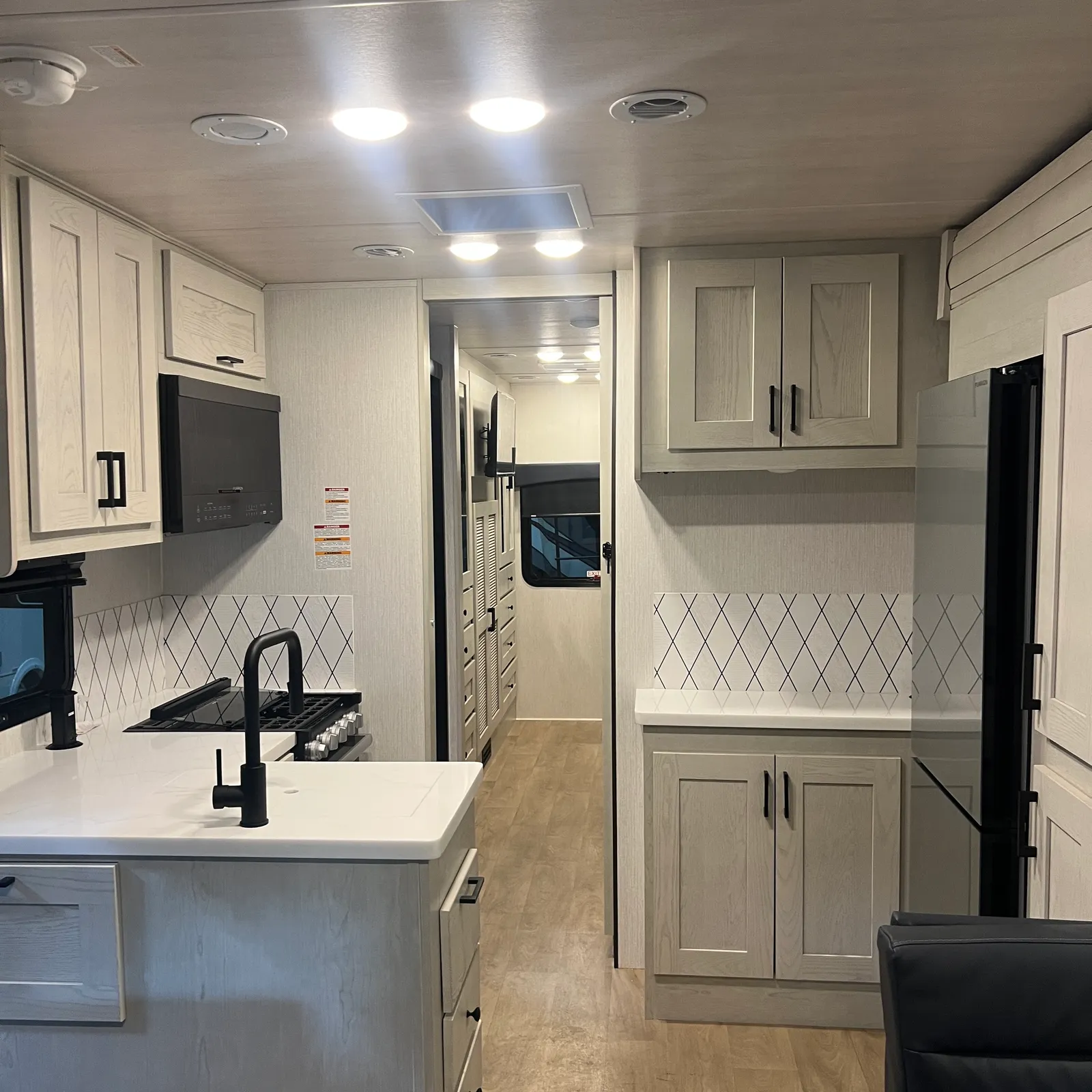 2027 Nexus Rebel AIR 34R Super C motorhome, kitchen with white cabinetry, black faucet, and diamond backsplash tile