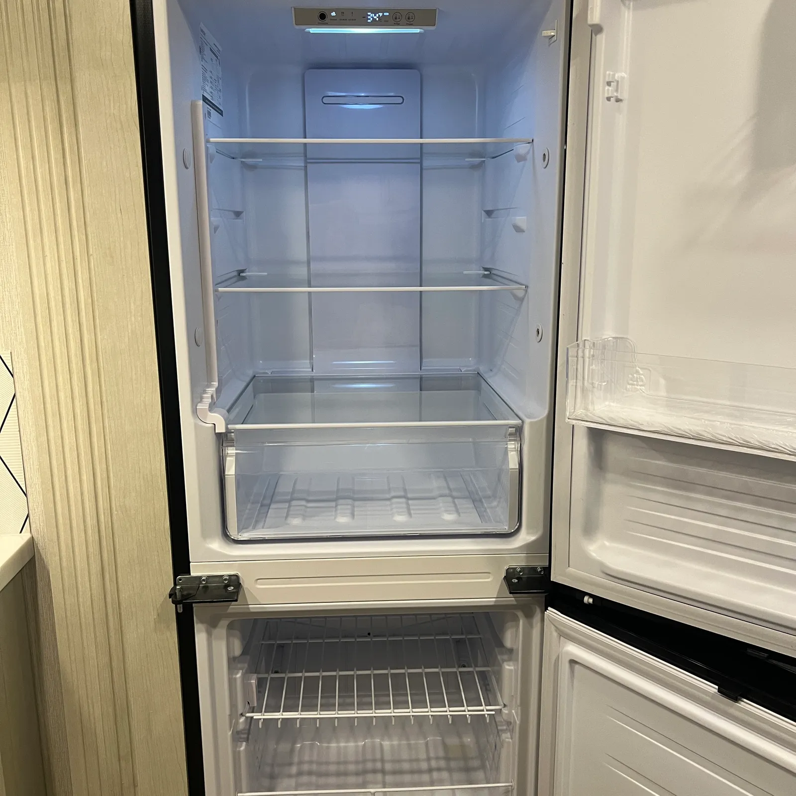 2027 Nexus Rebel AIR 34R Super C motorhome, open refrigerator with empty shelves and freezer compartment