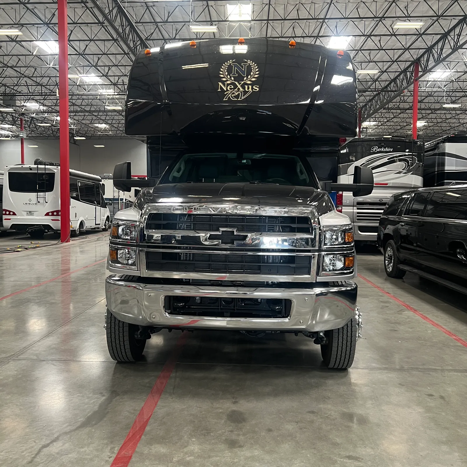 2027 Nexus Rebel AIR 34R Super C motorhome, black nexus motorhome mounted on silver pickup truck in dealer showroom