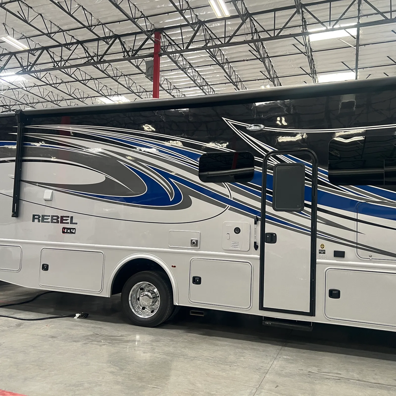 2027 Nexus Rebel AIR 34R Super C motorhome, white motorhome with blue and black graphics in indoor storage facility