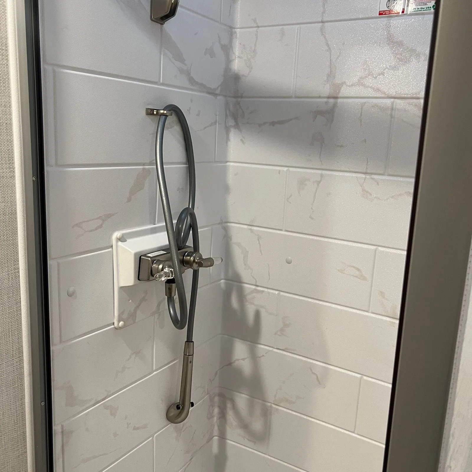 2026 Thor Delano 24XL Class C motorhome, shower interior with white subway tile walls and handheld showerhead
