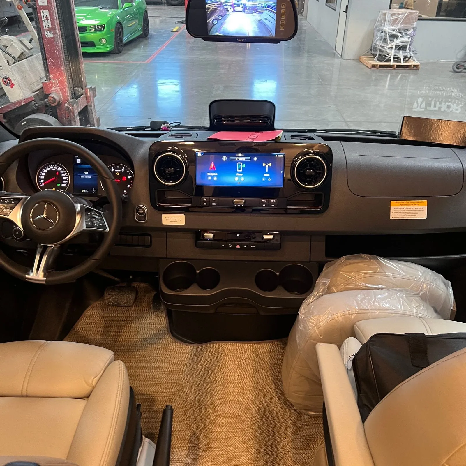 2026 Thor Delano 24XL Class C motorhome, driver's area with steering wheel, dashboard, touchscreen display, and tan seats