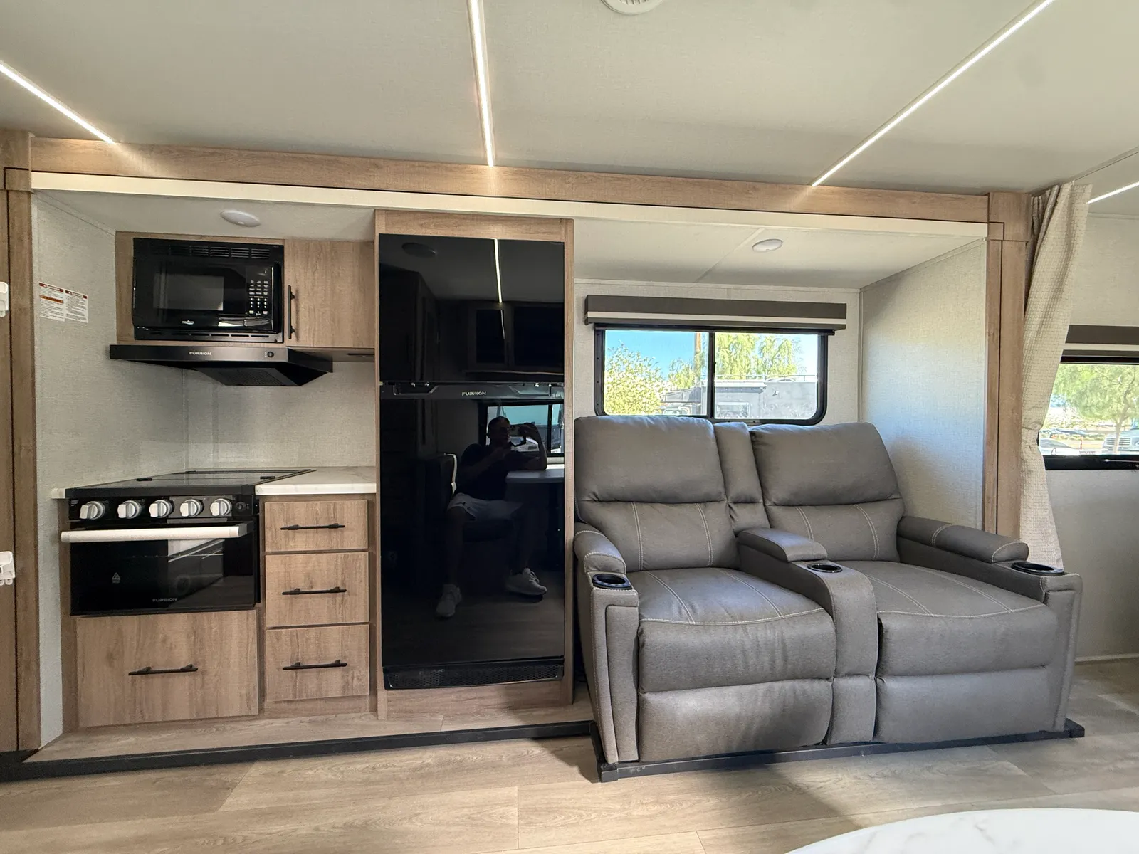2024 Grand Design Imagine Xls 22MLE Travel Trailer motorhome, living area with gray recliners, kitchen with stove and microwave, windows with views