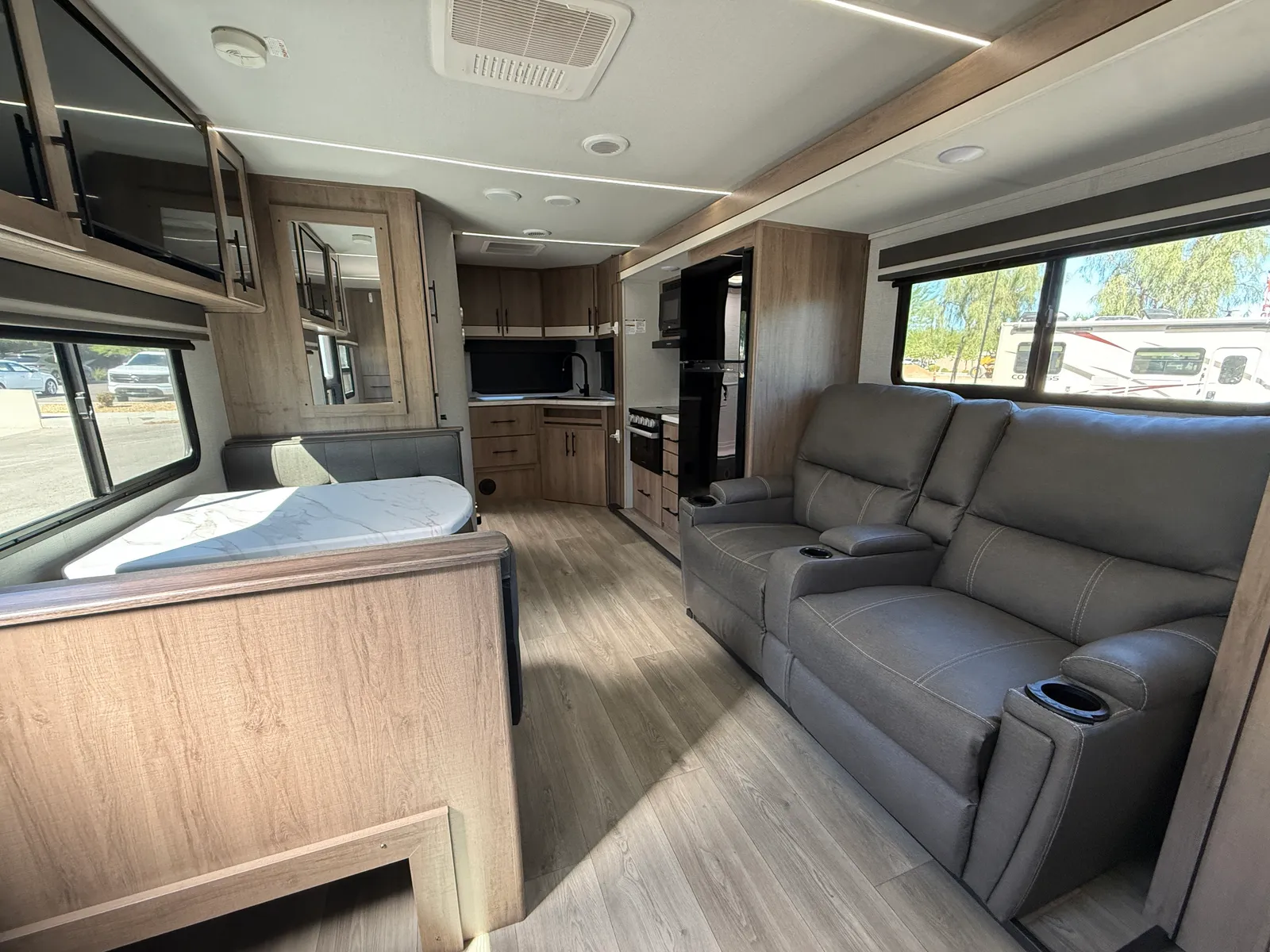 2024 Grand Design Imagine Xls 22MLE Travel Trailer motorhome, living area with gray leather sofa, dinette, and galley kitchen