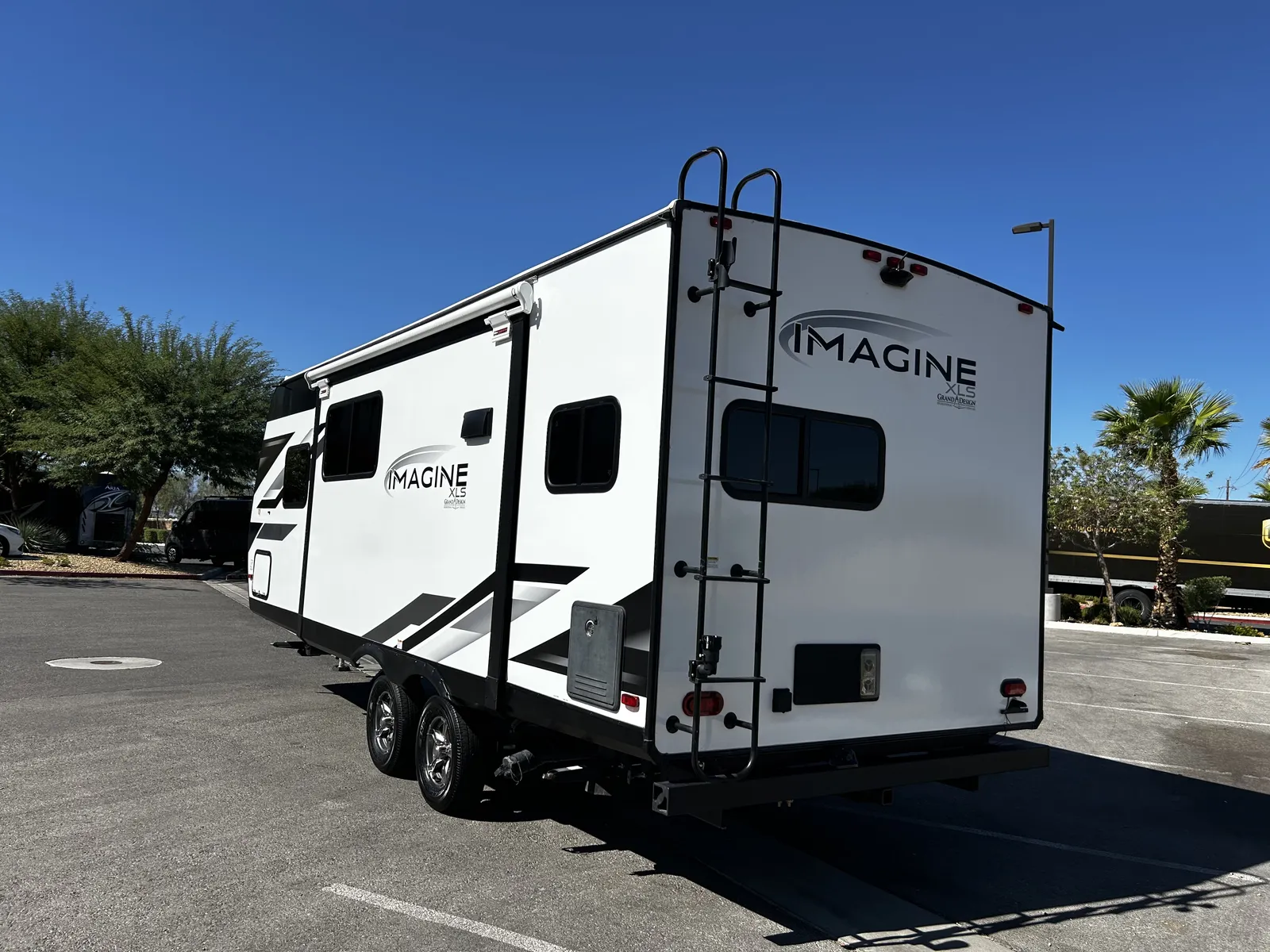 2024 Grand Design Imagine Xls 22MLE Travel Trailer motorhome, white travel trailer with black trim and roof ladder parked outdoors