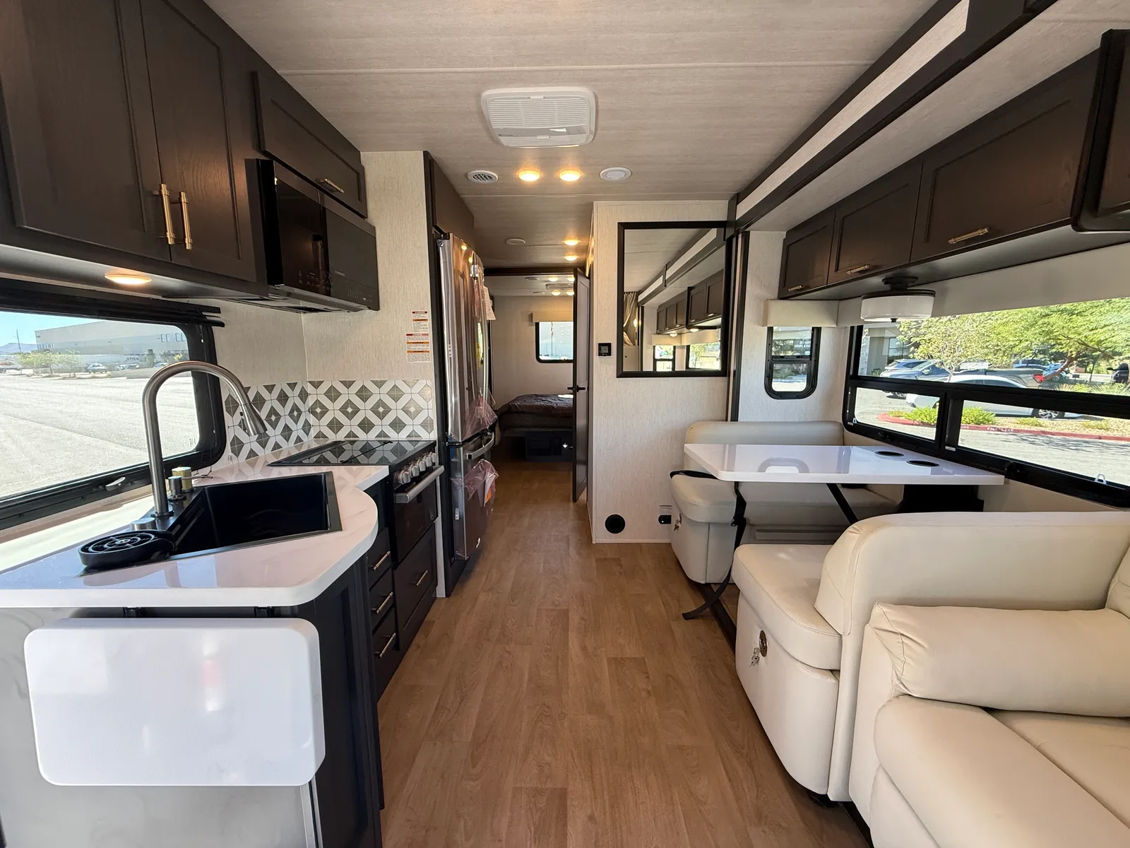 2027 Nexus Ghost 36DS Super C motorhome, open concept living area with galley kitchen, dinette, and cream upholstered seating