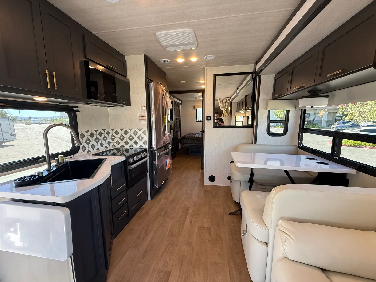 2027 Nexus Ghost 36DS Super C motorhome, galley and living area with black cabinets, sink, stove, and cream seating