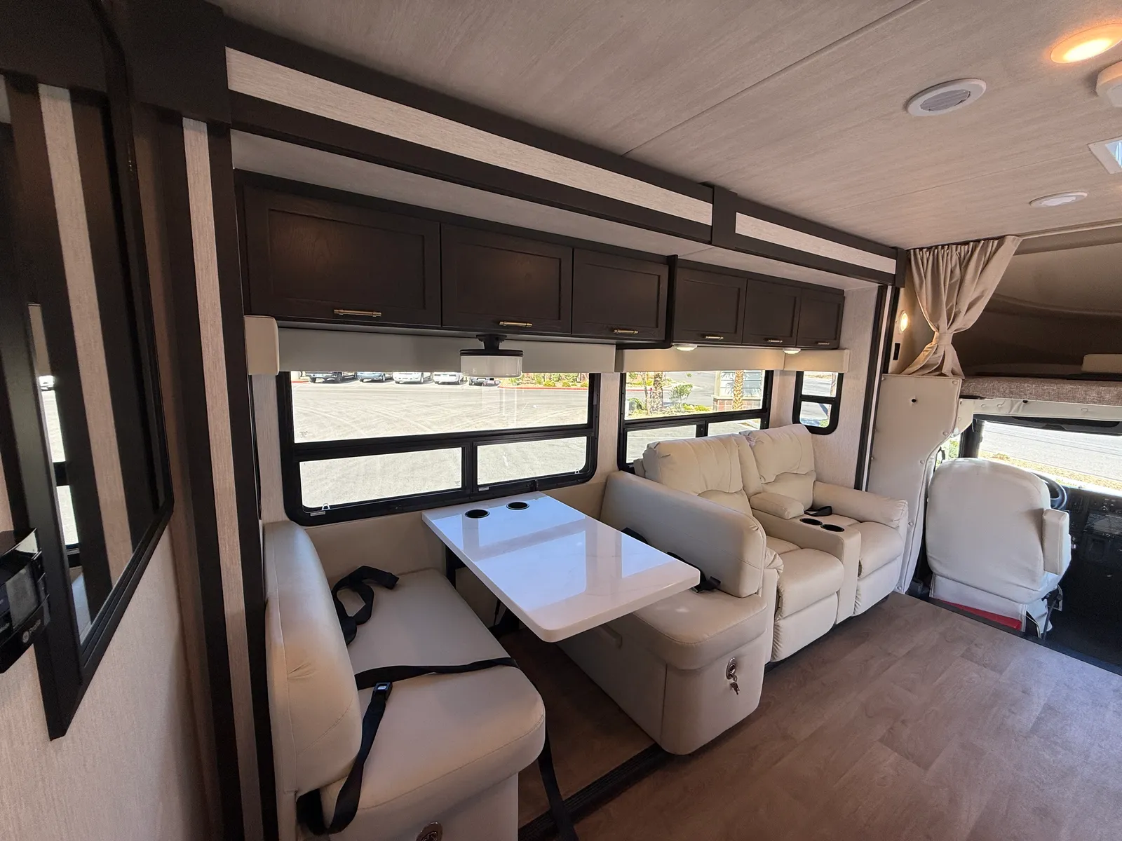 2027 Nexus Ghost 36DS Super C motorhome, living area with cream seating, white table, and large windows