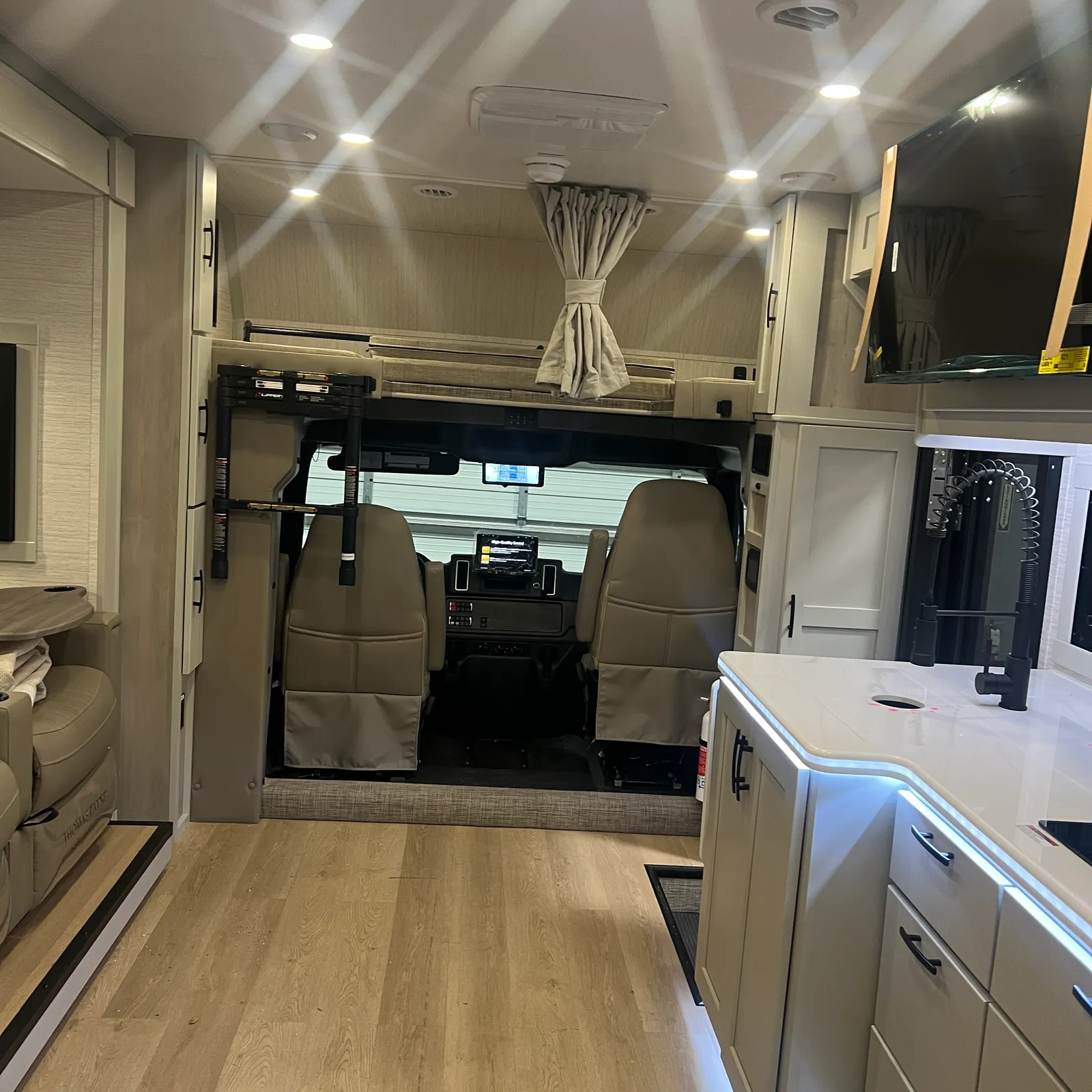 2027 Dynamax Corp Europa 31SS Super C motorhome, living area with galley, cockpit view, and wood flooring