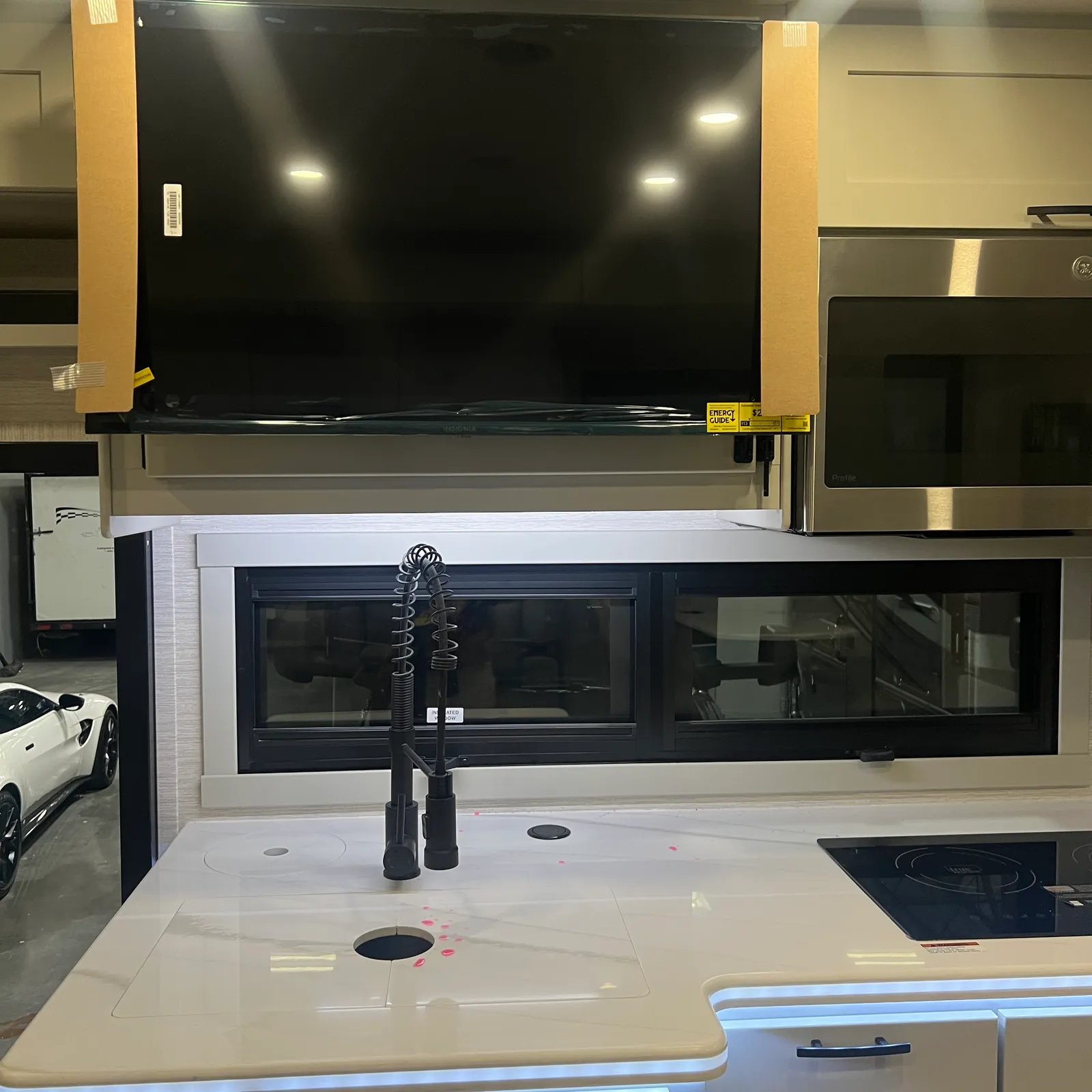 2027 Dynamax Corp Europa 31SS Super C motorhome, kitchen with white countertop, black faucet, and overhead television