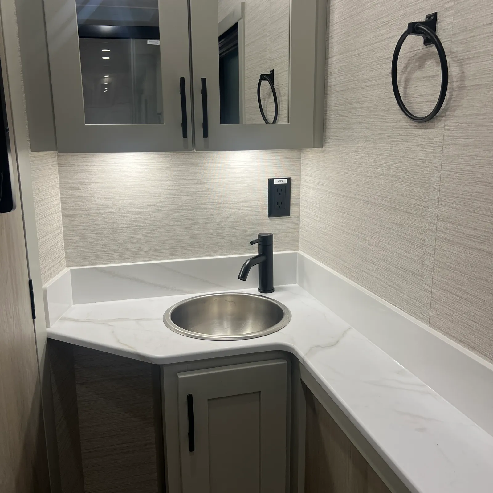 2027 Dynamax Corp Europa 31SS Super C motorhome, bathroom with round sink, black faucet, mirror cabinet, and tile walls