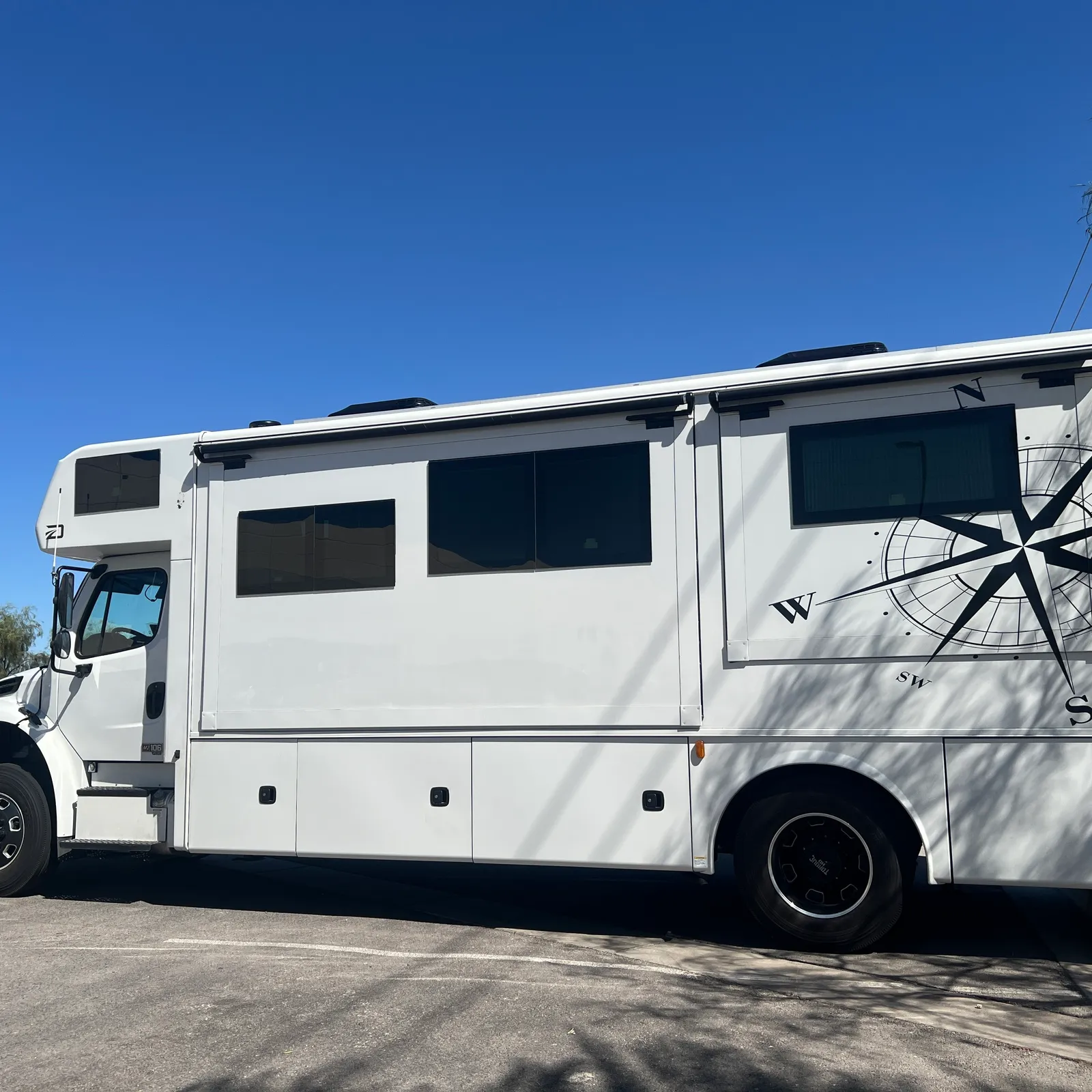 2027 Dynamax Corp Europa 31SS Super C motorhome, white motorhome with multiple windows and compass rose graphic detail