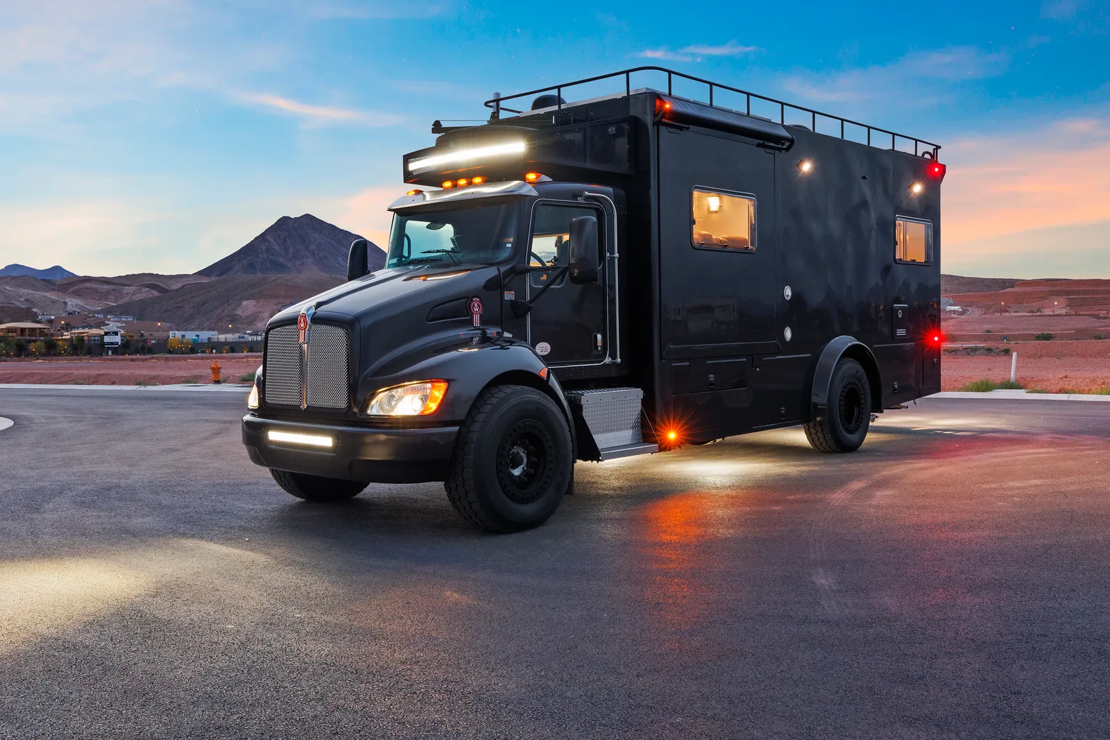 2017 Global Expedition Vehicles The Beast Off Grid Extreme RV Super C motorhome, black motorhome on truck chassis with roof rack and lighting in desert landscape